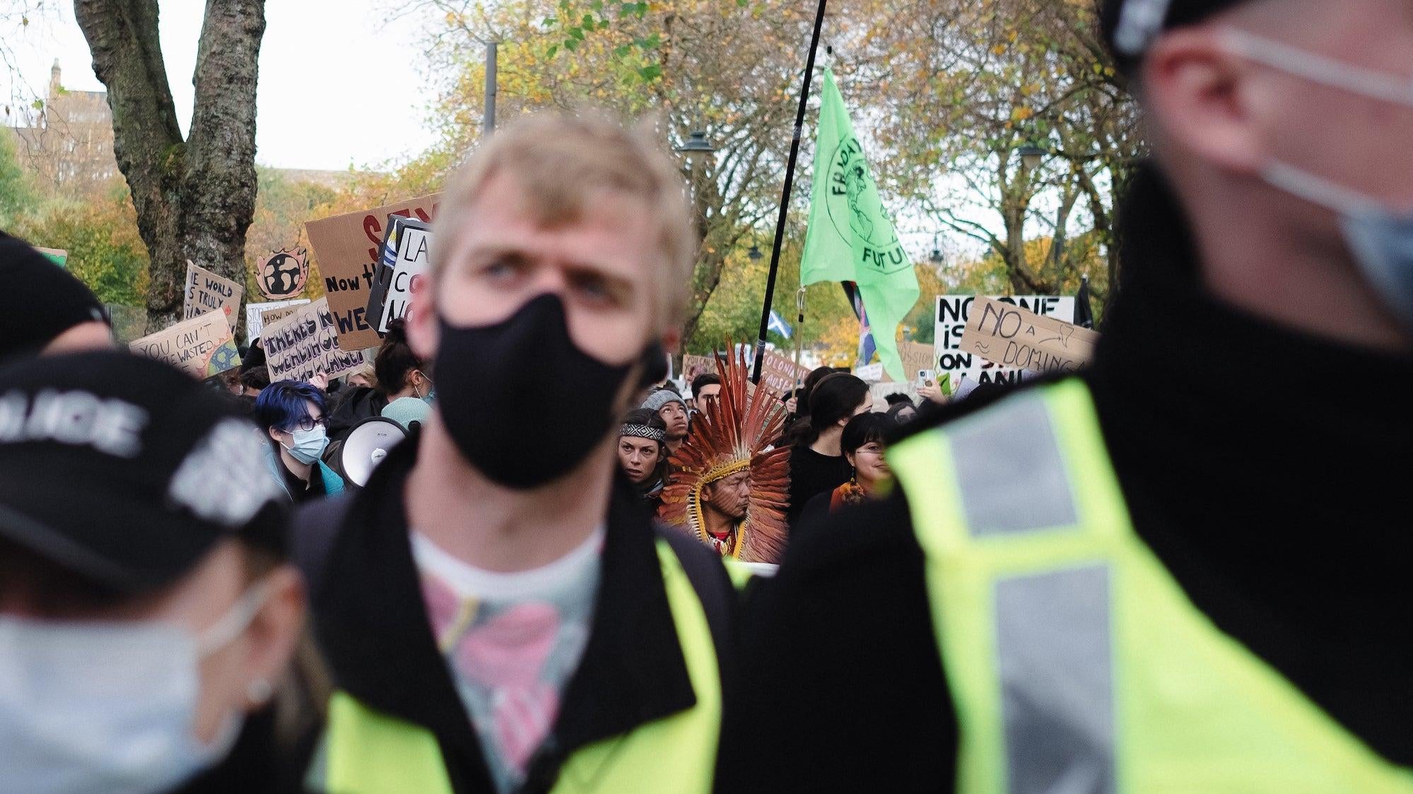 An Indigenous protester seen through a sea of police officers.