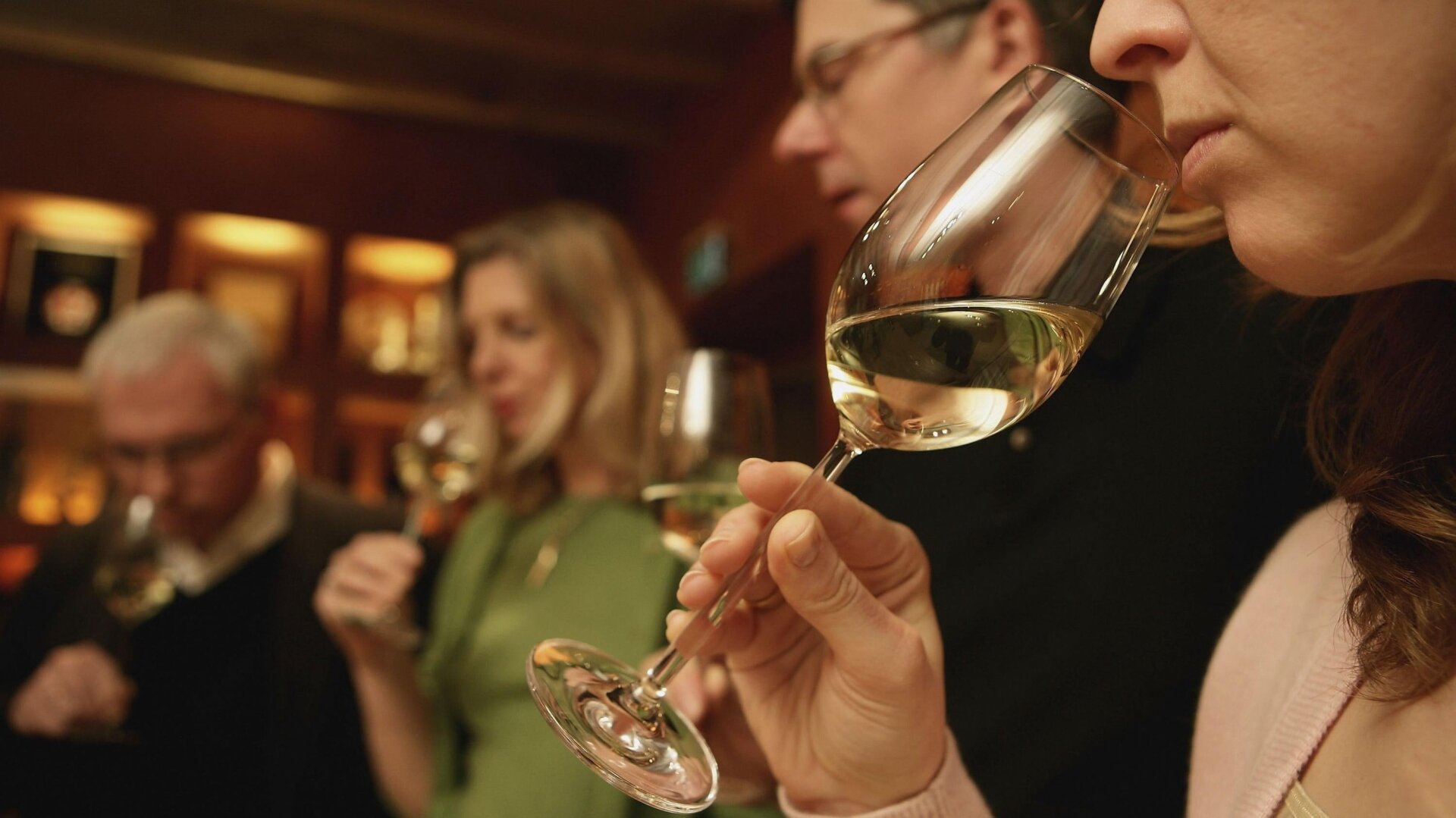 People conducting a wine tasting, which involves sniffing the wine.