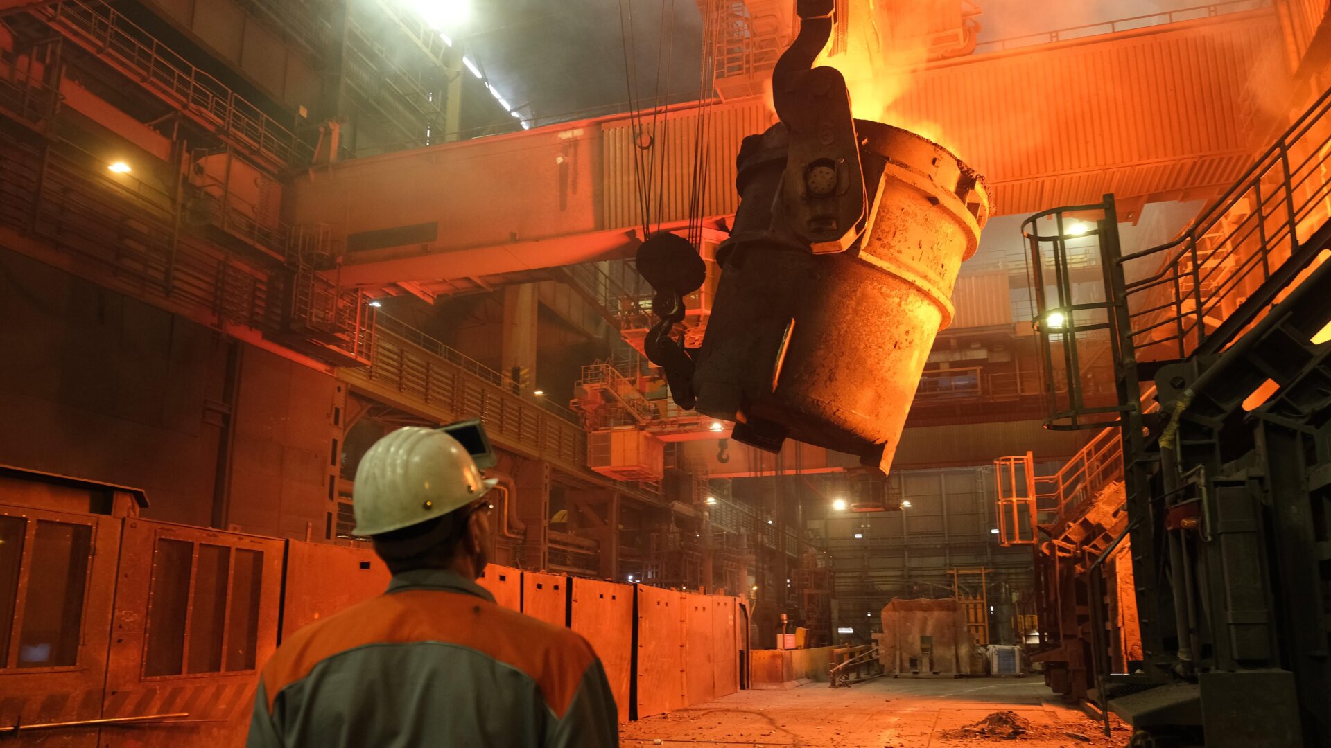 A worker watches as a ladle recedes after pouring molten iron into a converter for creating steel at the Salzgitter AG steelworks in Germany.