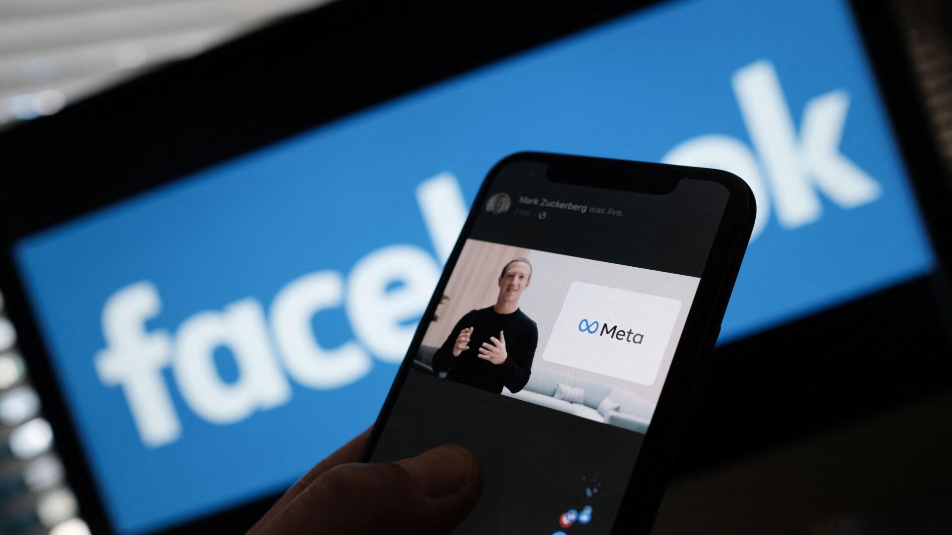 A smartphone showing Facebook founder Mark Zuckerberg talking about the “metaverse” overlaid over the Facebook logo.