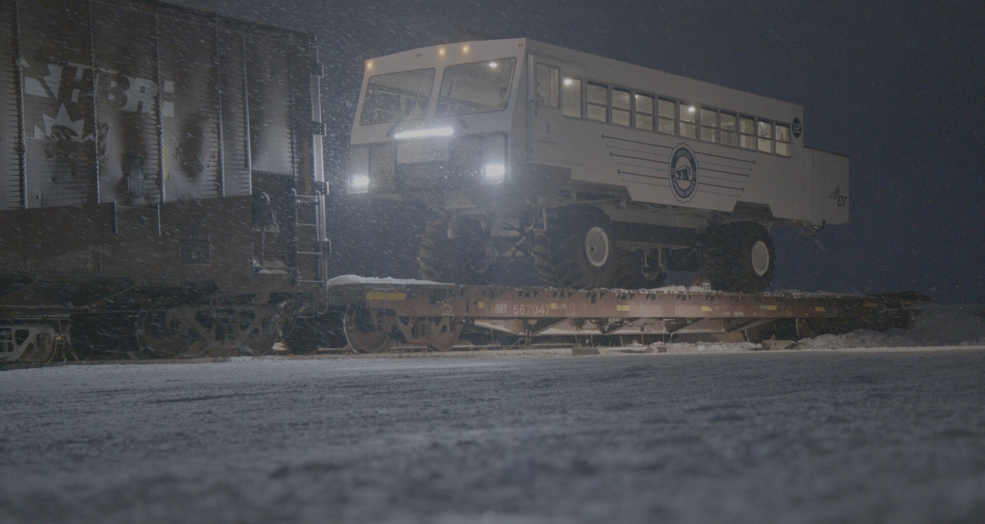 The electric Tundra Buggy on a flatbed at night.