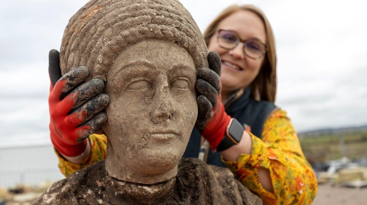 Archaeologist Rachel Wood positioning a stone bust atop its corresponding torso.