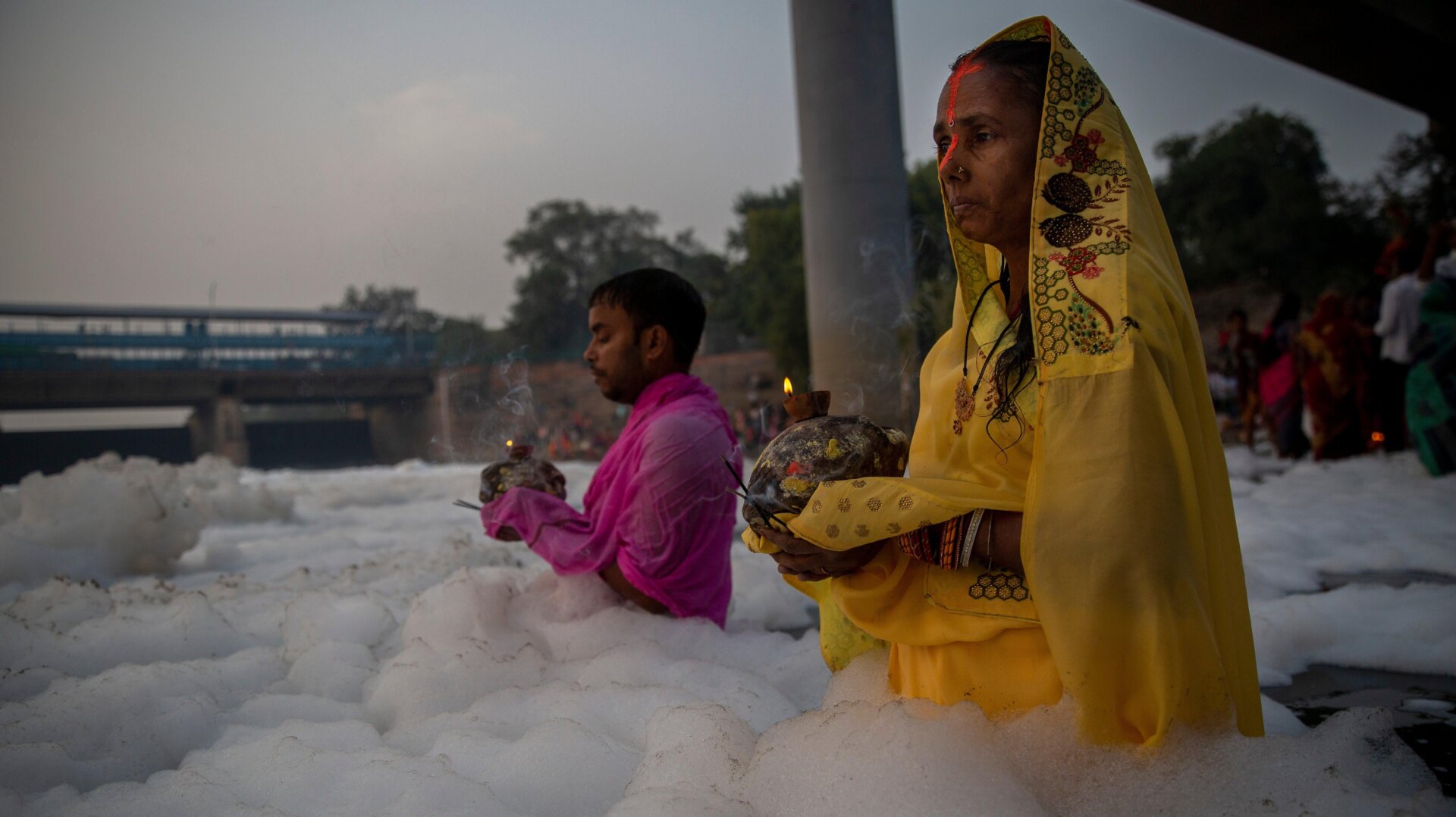 People perform rituals in Yamuna river, covered by chemical foam caused due to industrial and domestic pollution, during Chhath Puja festival.