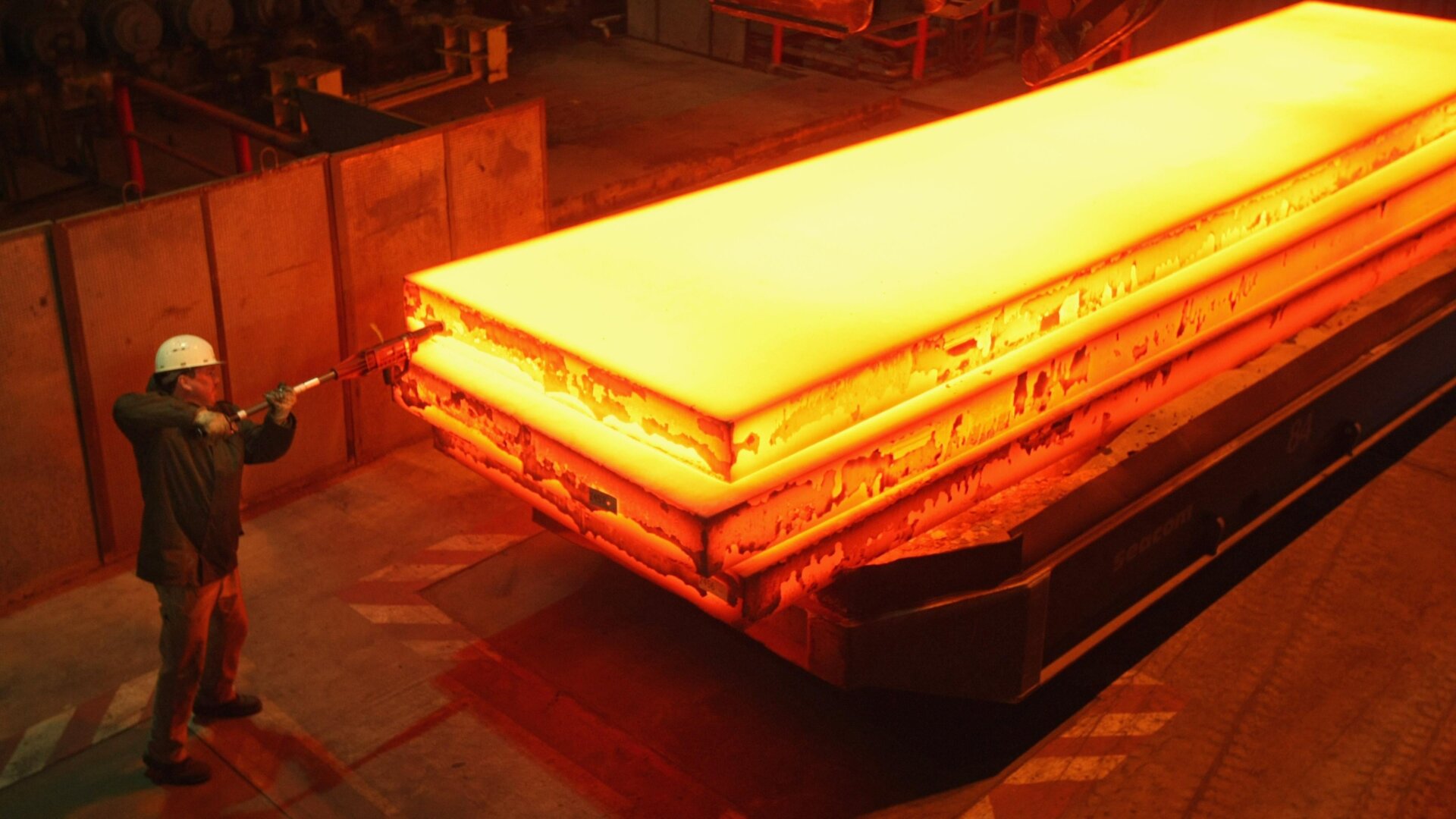 A worker tags a giant block of heated steel at the rolling mill at the ThyssenKrupp steelworks in Germany.