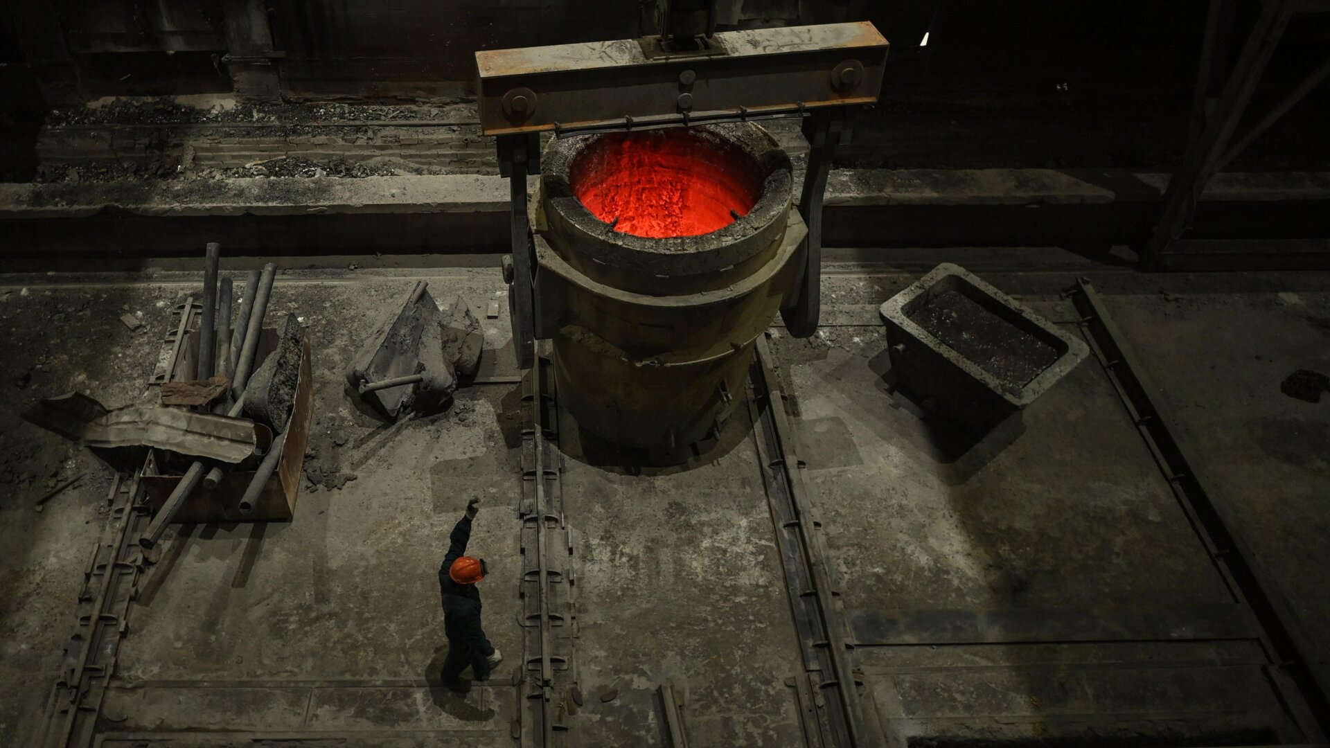A worker gives signs to a crane operator to transport cast steel during a government organized tour at a Tiangong International plant.