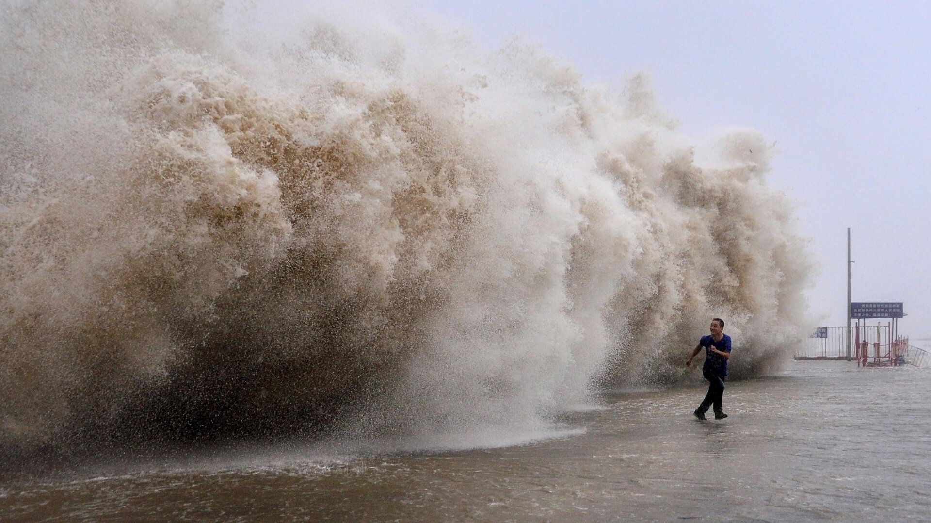 A man running away from a huge wave pushed up by Typhoon Usagi on a wharf in Shantou, China.