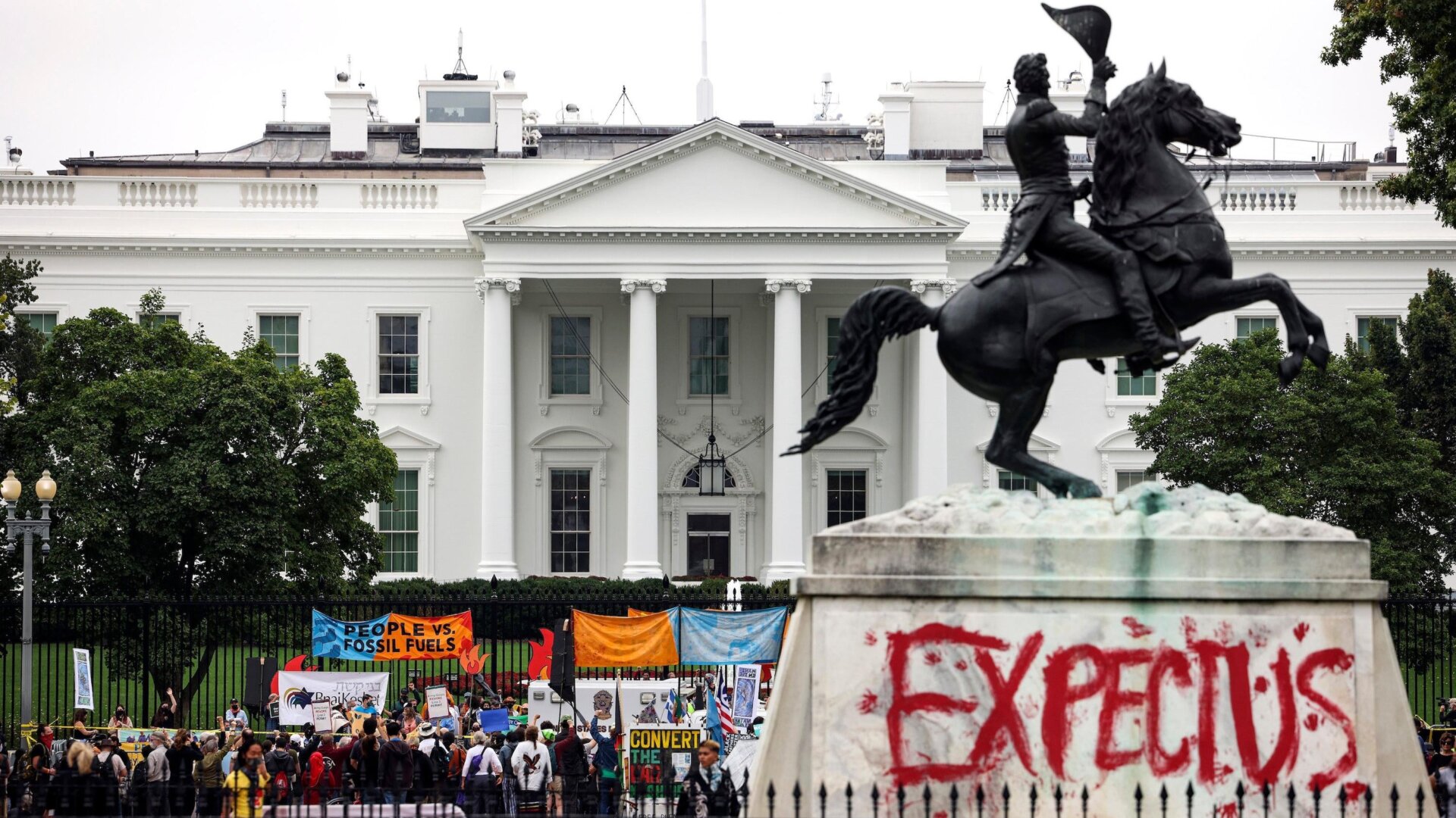Climate protesters demonstrate alongside a tagged statue of President Andrew Jackson at the White House.