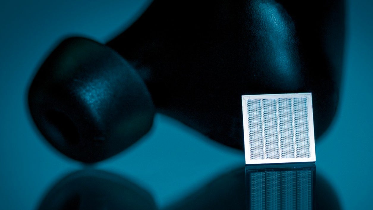 “An Arioso Systems silicon microspeaker in front of a wireless in-ear headphone.”
