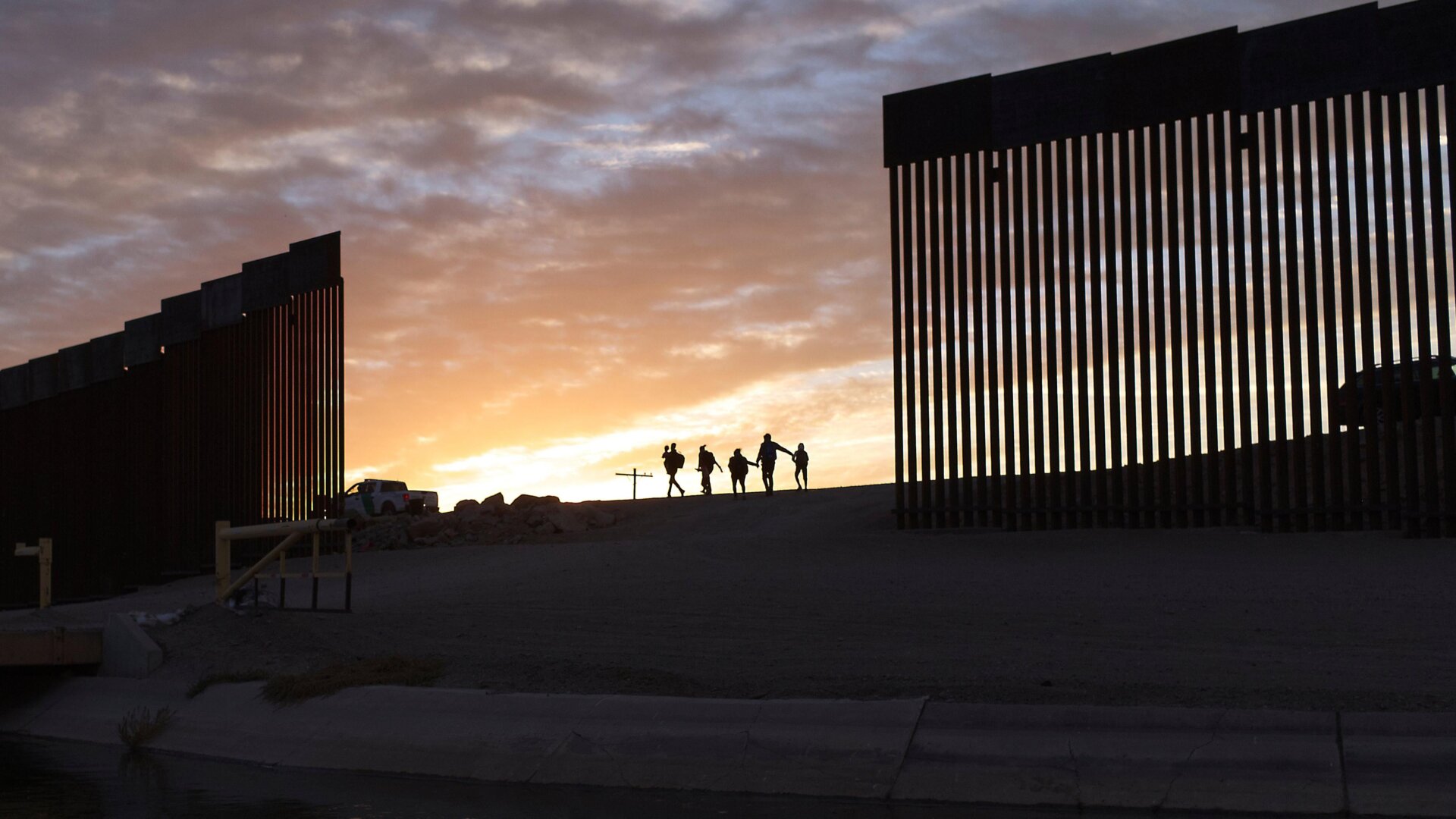 Two migrant families from Brazil pass through a gap in the border wall to seek asylum in the the United States on June 20, 2021