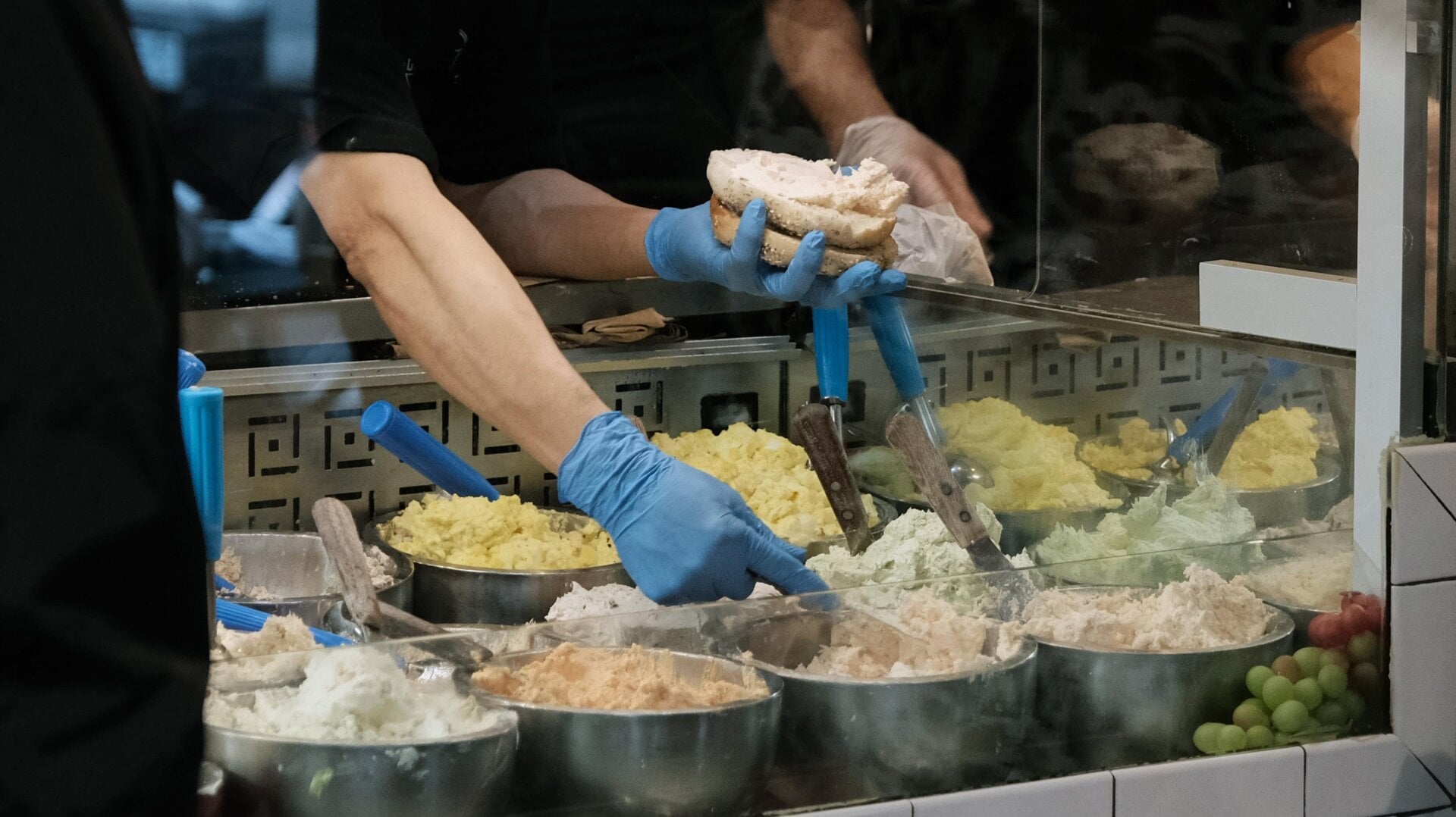 Cream cheese being slapped onto a bagel at one of the Manhattan locations of Pick a Bagel on Dec. 6, 2021.