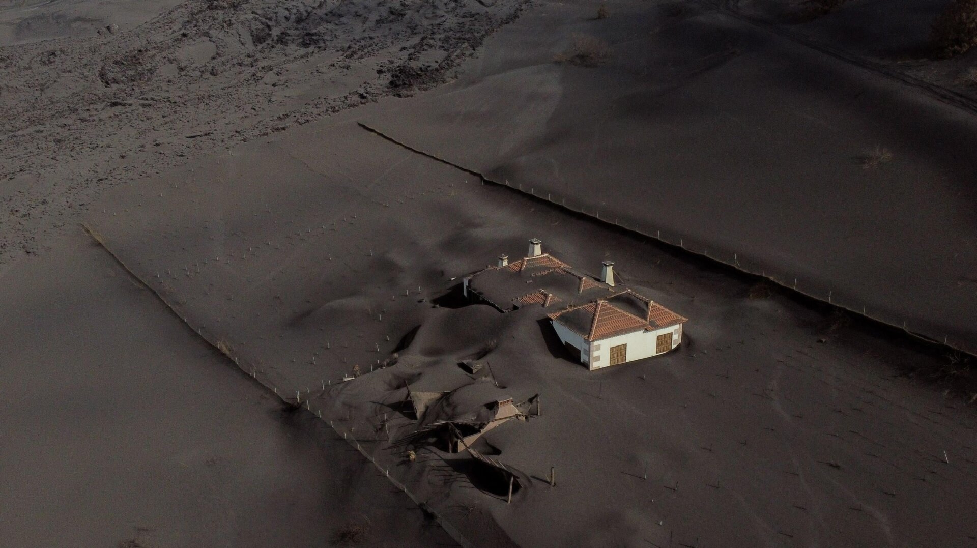 This aerial picture shows a house covered with lava and ashes following the eruption of the Cumbre Vieja volcano in Las Manchas on the Canary Island of La Palma on Dec. 14, 2021.