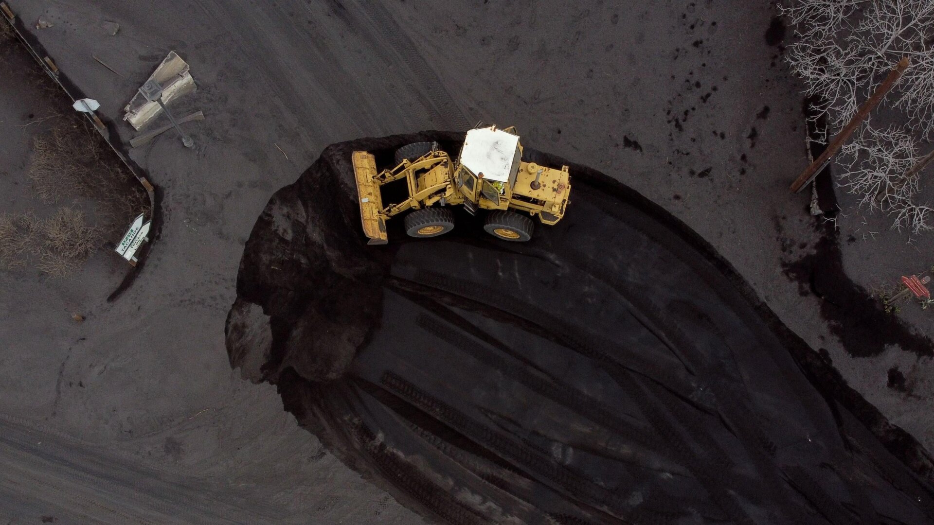 An excavator removes ashes from a street covered in lava and ashes following the eruption of the Cumbre Vieja volcano in Las Manchas on the Canary Island of La Palma on Dec. 14, 2021.