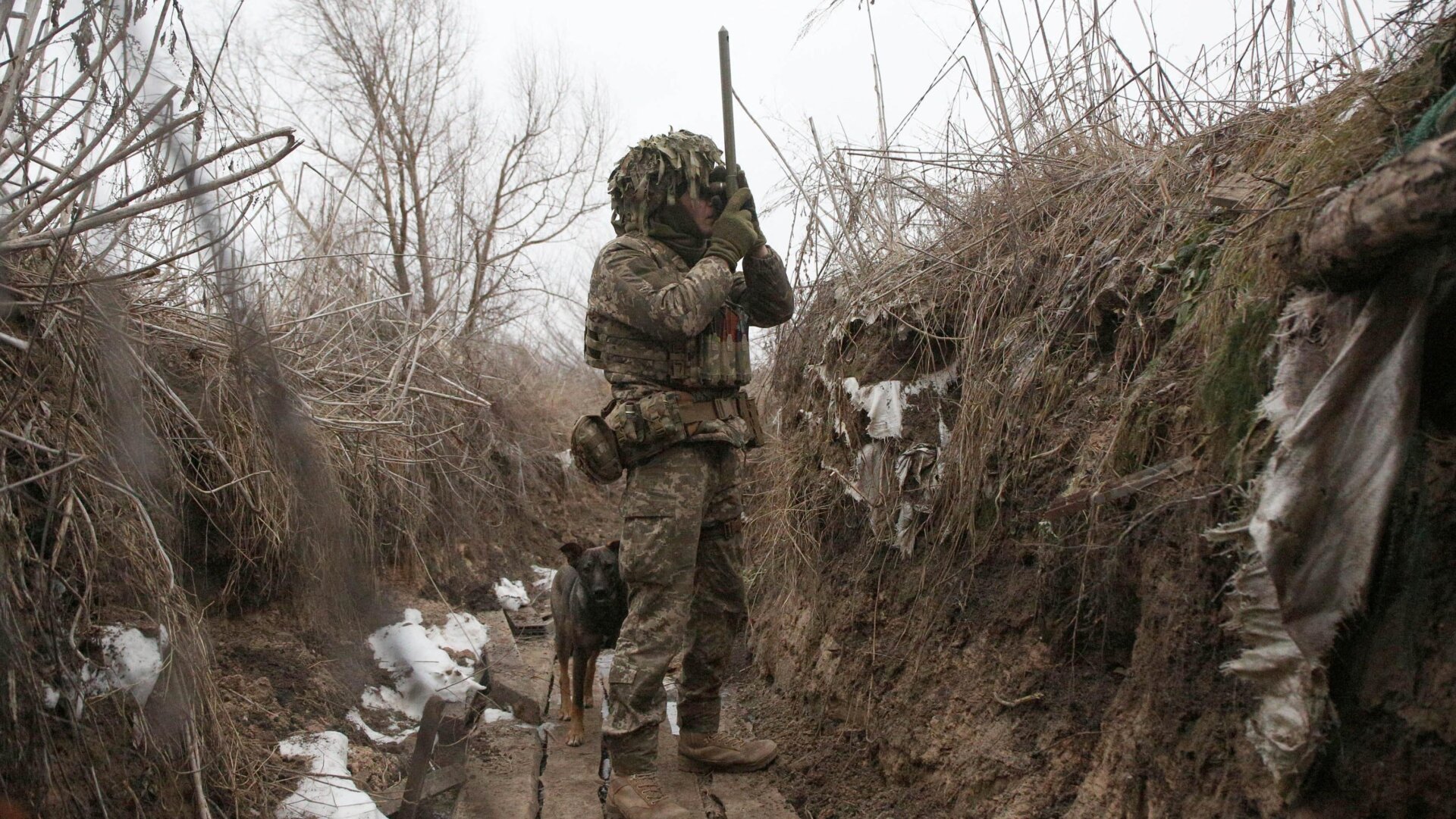 Ukrainian Military Forces serviceman watches through spyglass in a trench on the frontline with Russia-backed separatists near Avdiivka, southeastern Ukraine, on January 9, 2022.