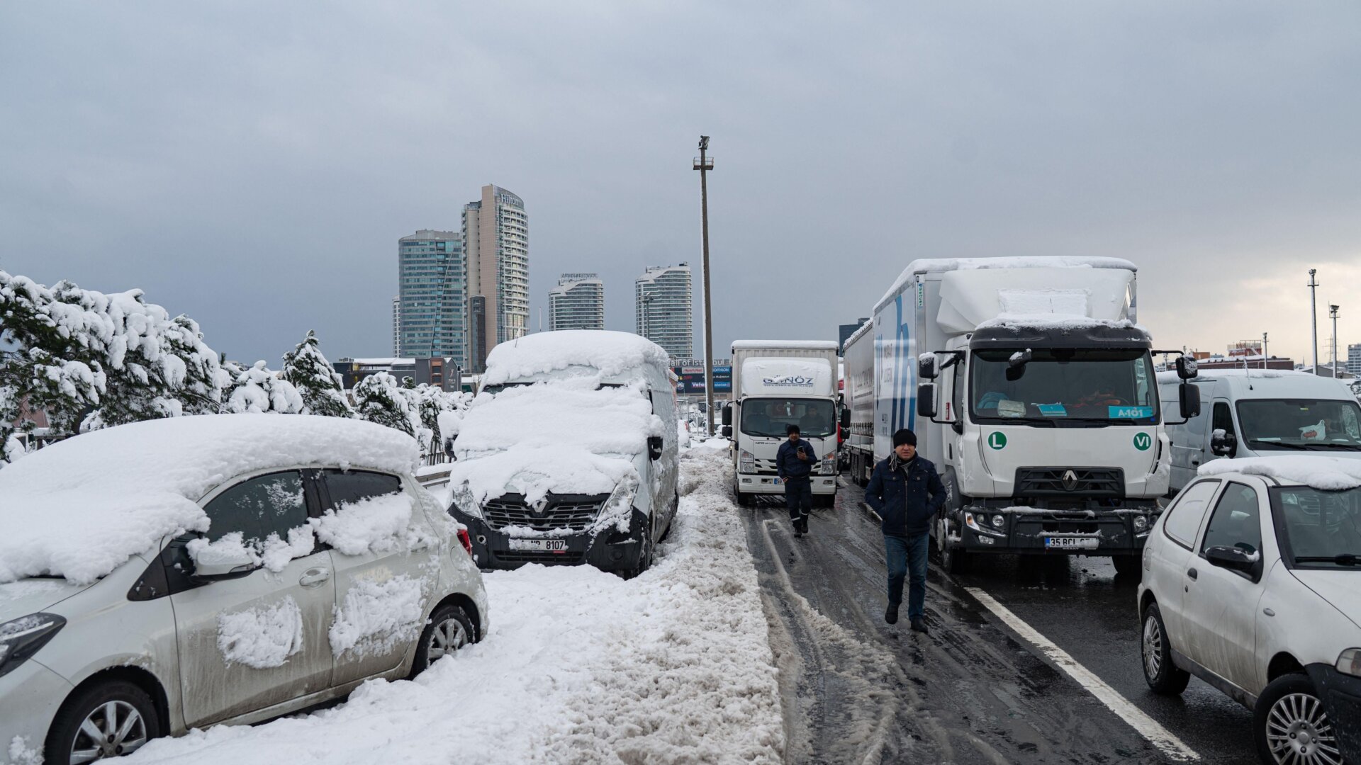 Men walk past vehicles stranded on the highway after heavy snowfall at the Basaksehir district in Istanbul.