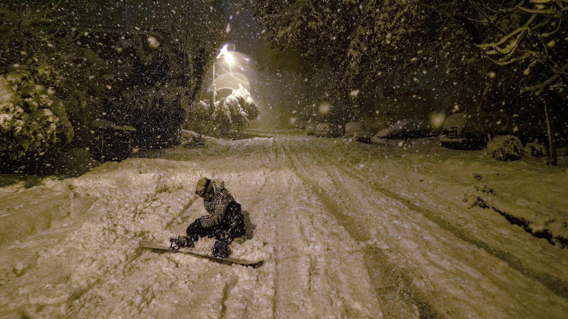 A snowboarder gets ready to go down a snow-covered street in Athens.