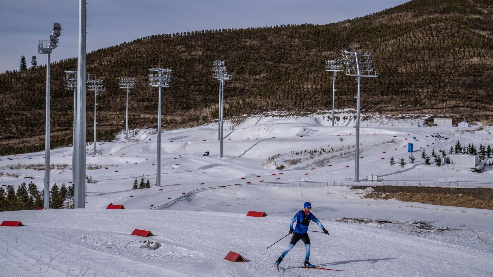 An athlete from Team France passes snowless hills as he takes part in a training session Zhangjiakou National Biathlon Centre on February 7, 2022 in Zhangjiakou, China. The Beijing 2022 Winter Olympics are held entirely on artificial snow.