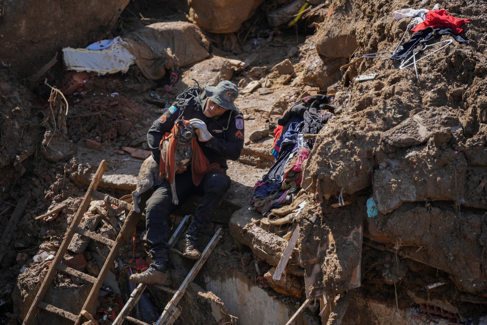 A rescue worker carries a dog away from a residential area destroyed by mudslides.