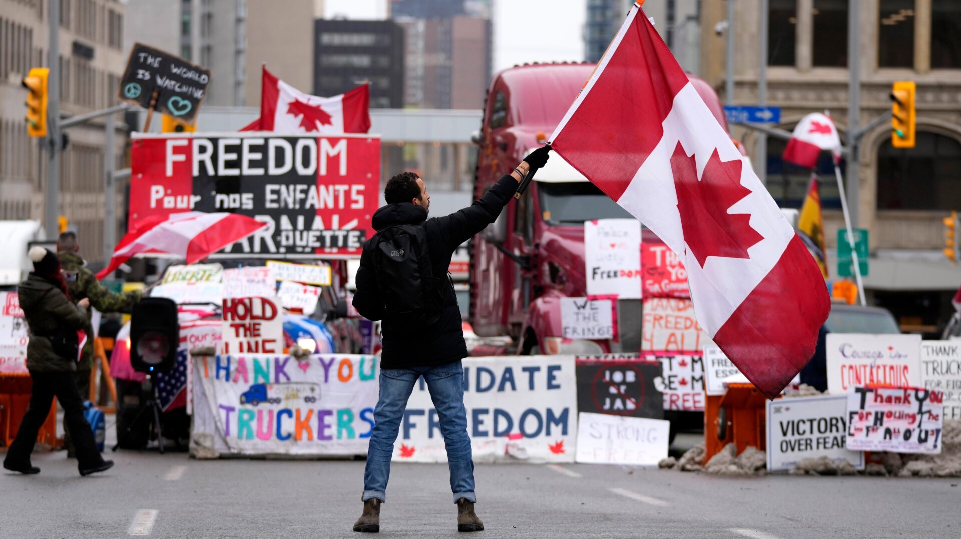 A protester waves a Canadian flag in front of parked vehicles on Rideau Street at a protest against COVID-19 measures that has grown into a broader anti-government protest, in Ottawa, Ontario, Friday, Feb. 11, 2022.
