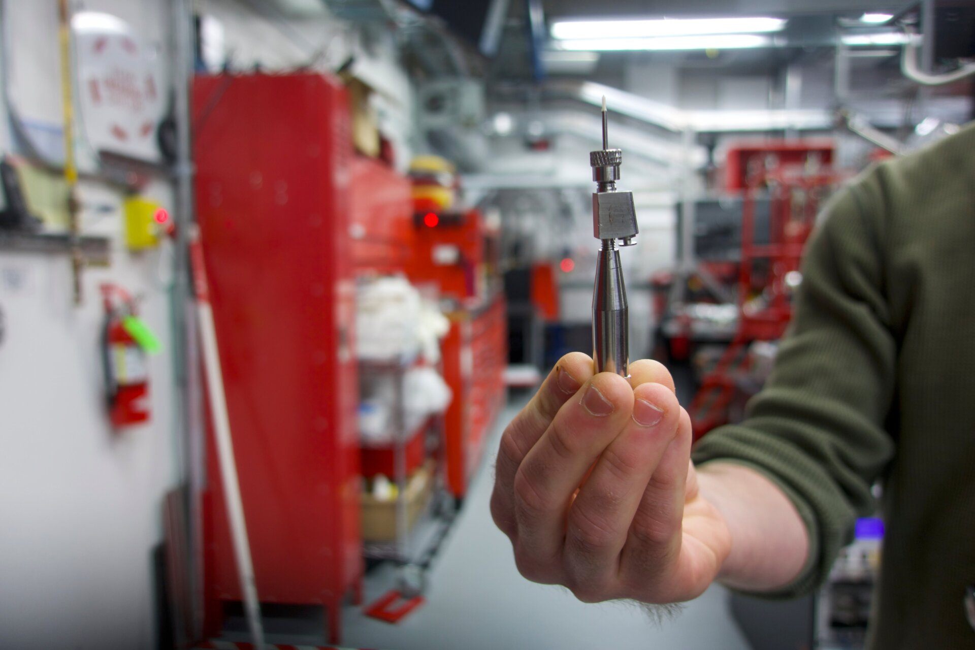 A researcher holds up a needle that emits sample in the Coherent X-ray Imaging instrument.