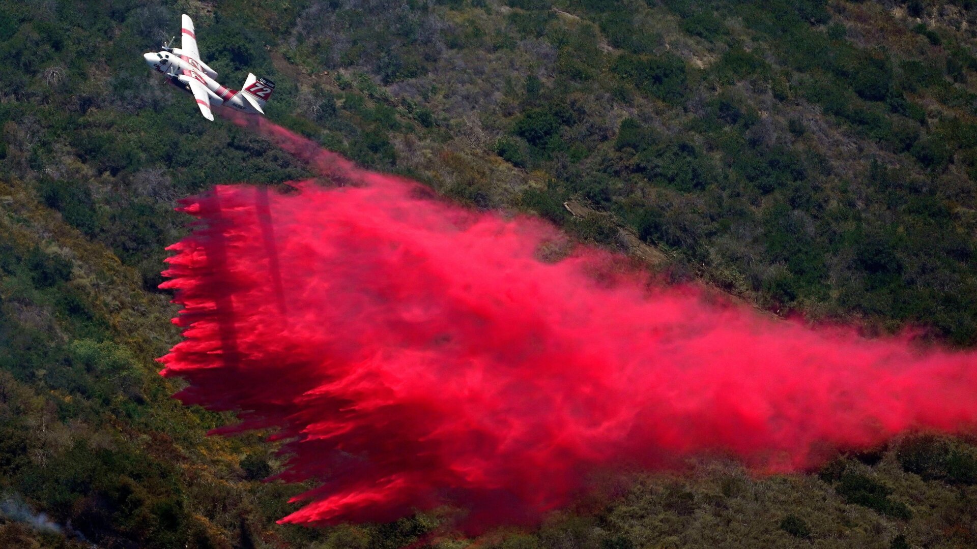 A plane drops fire retardant onto the Coastal Fire on Thursday, May 12, 2022, in Laguna Niguel, Calif. 