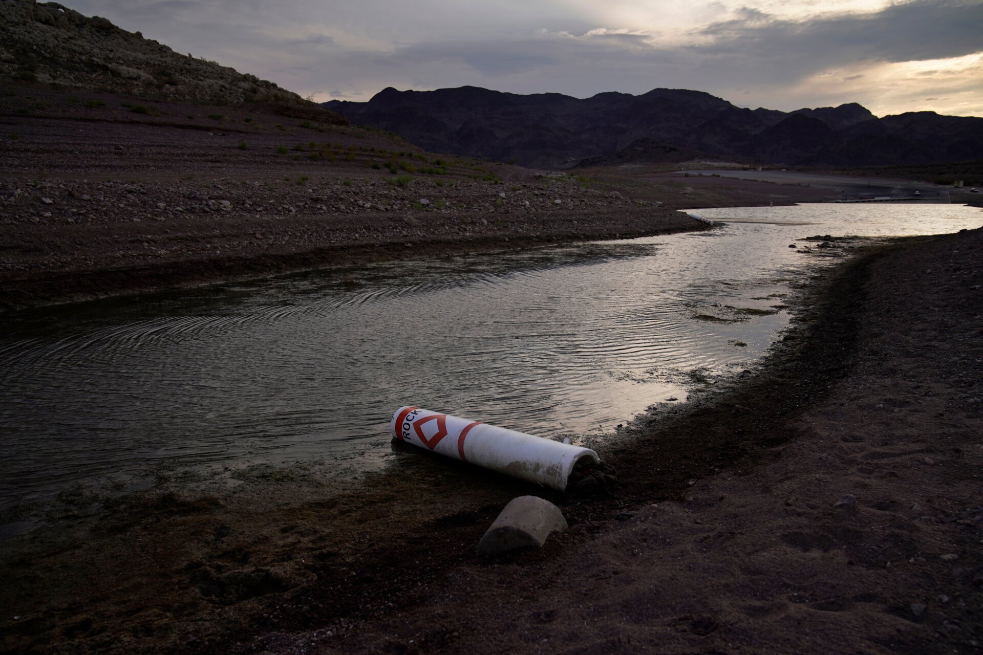 A buoy once used to warn of a submerged rock rests on the ground along the waterline near a closed boat ramp on Lake Mead.