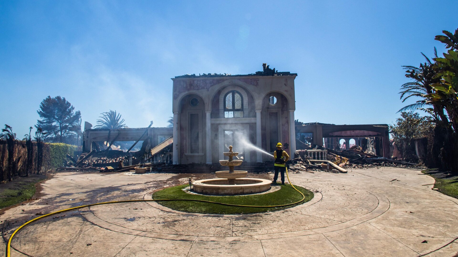 A firefighter uses a hose on one of the homes destroyed by the Coastal Fire in Laguna Niguel, California, May 12, 2022. 