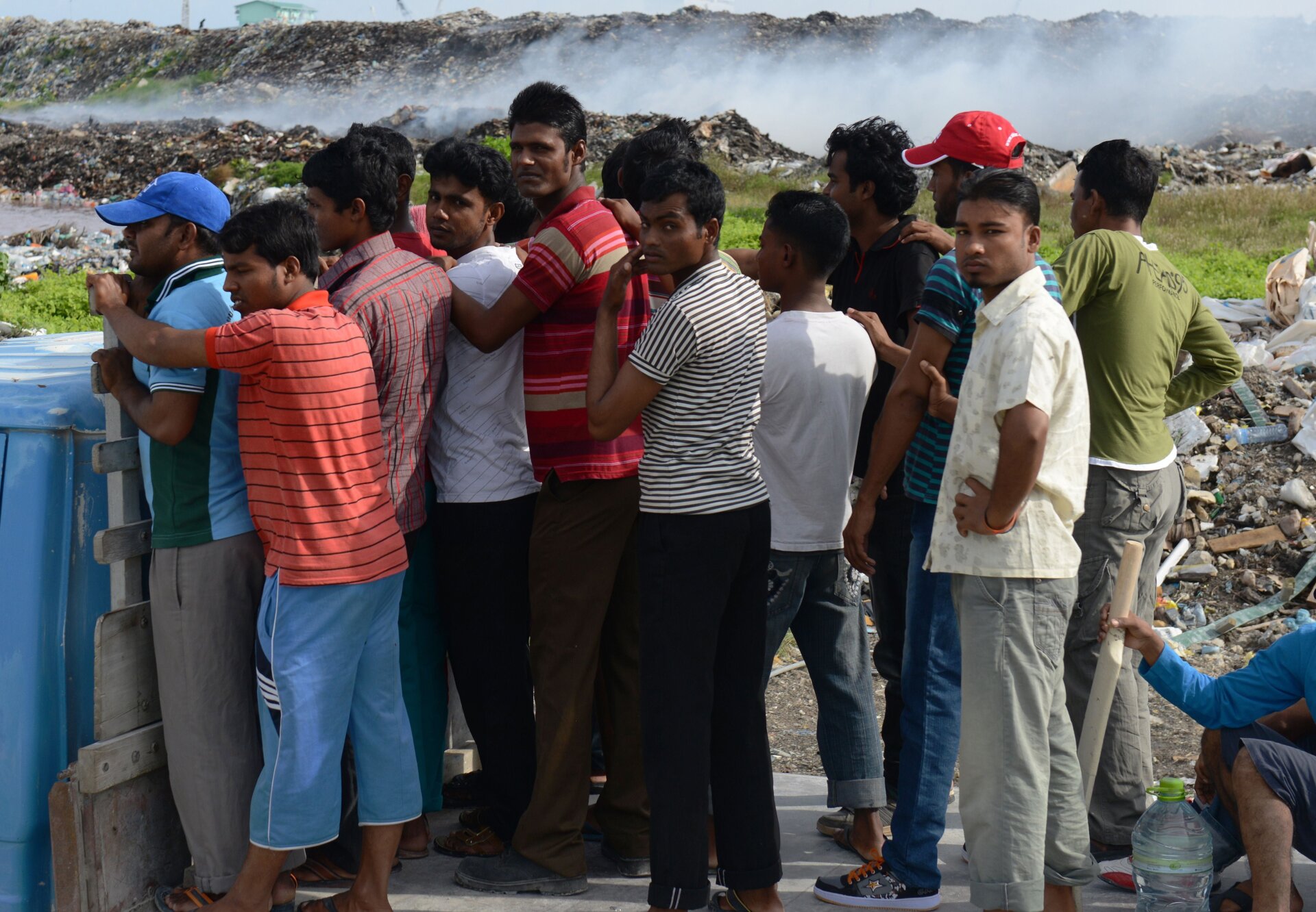 In this September 2013 photo, laborers ride on a truck past a burning trash heap on Thilafushi.