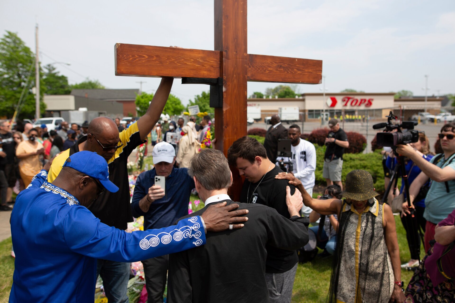 A group prays at the site of a memorial for the victims of the Buffalo supermarket shooting outside the Tops Friendly Market.