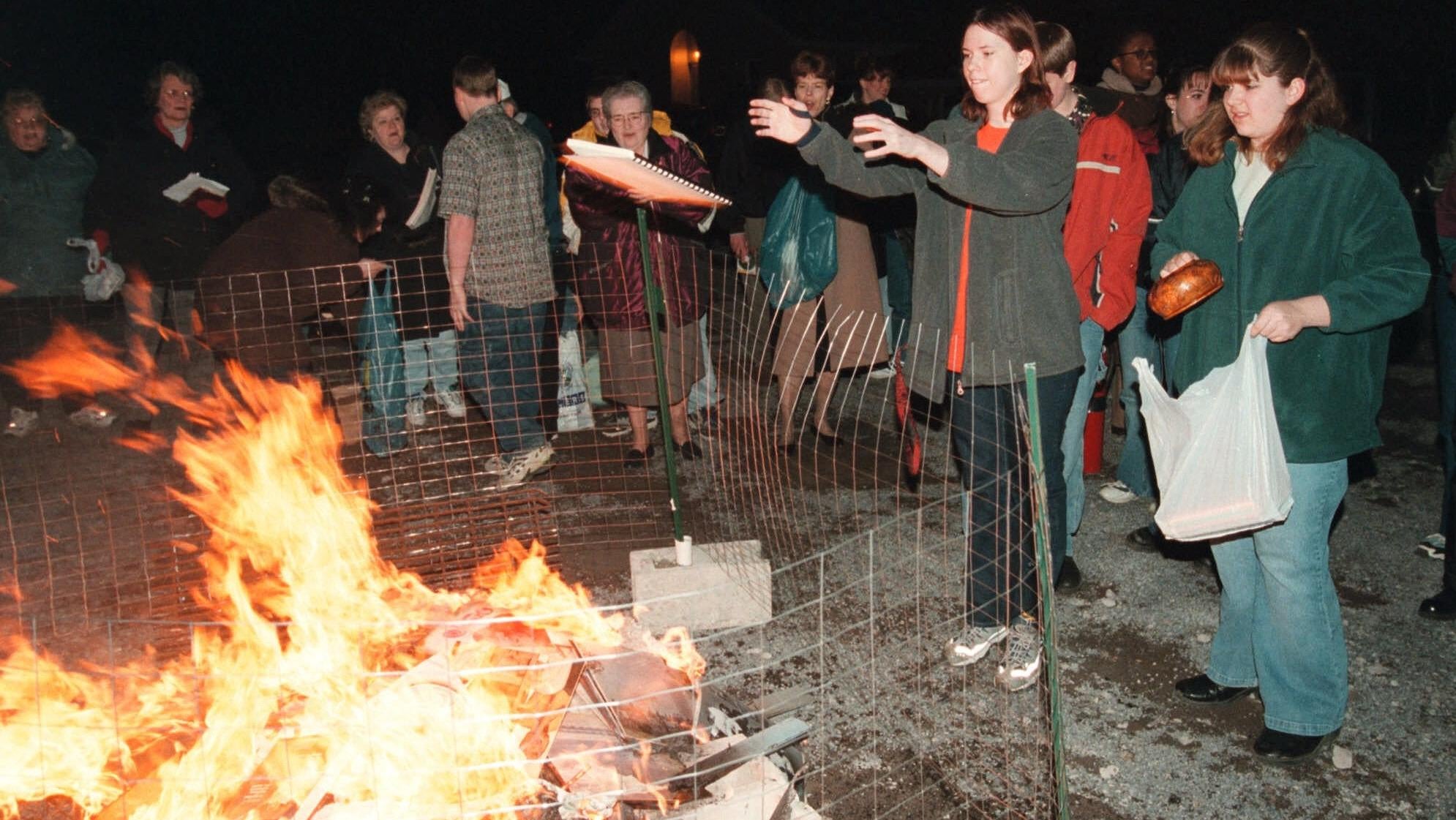 Members of the Harvest Assembly of God Church congregation toss items like books and CDs into a fire in 2001.