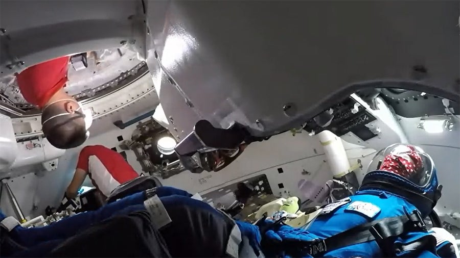 NASA astronauts inspecting the Starliner interior, with Rosie the Rocketeer (a manikin) still strapped to her seat.