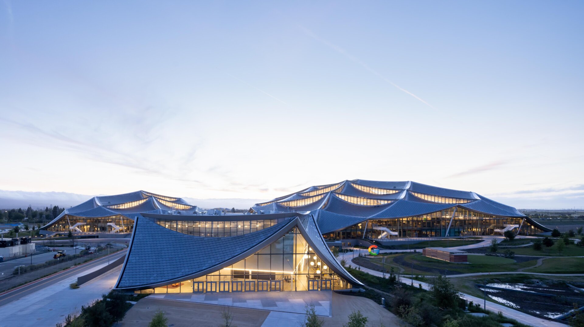 The Bay View Campus at night with Google’s signature colorful G logo in front of it.