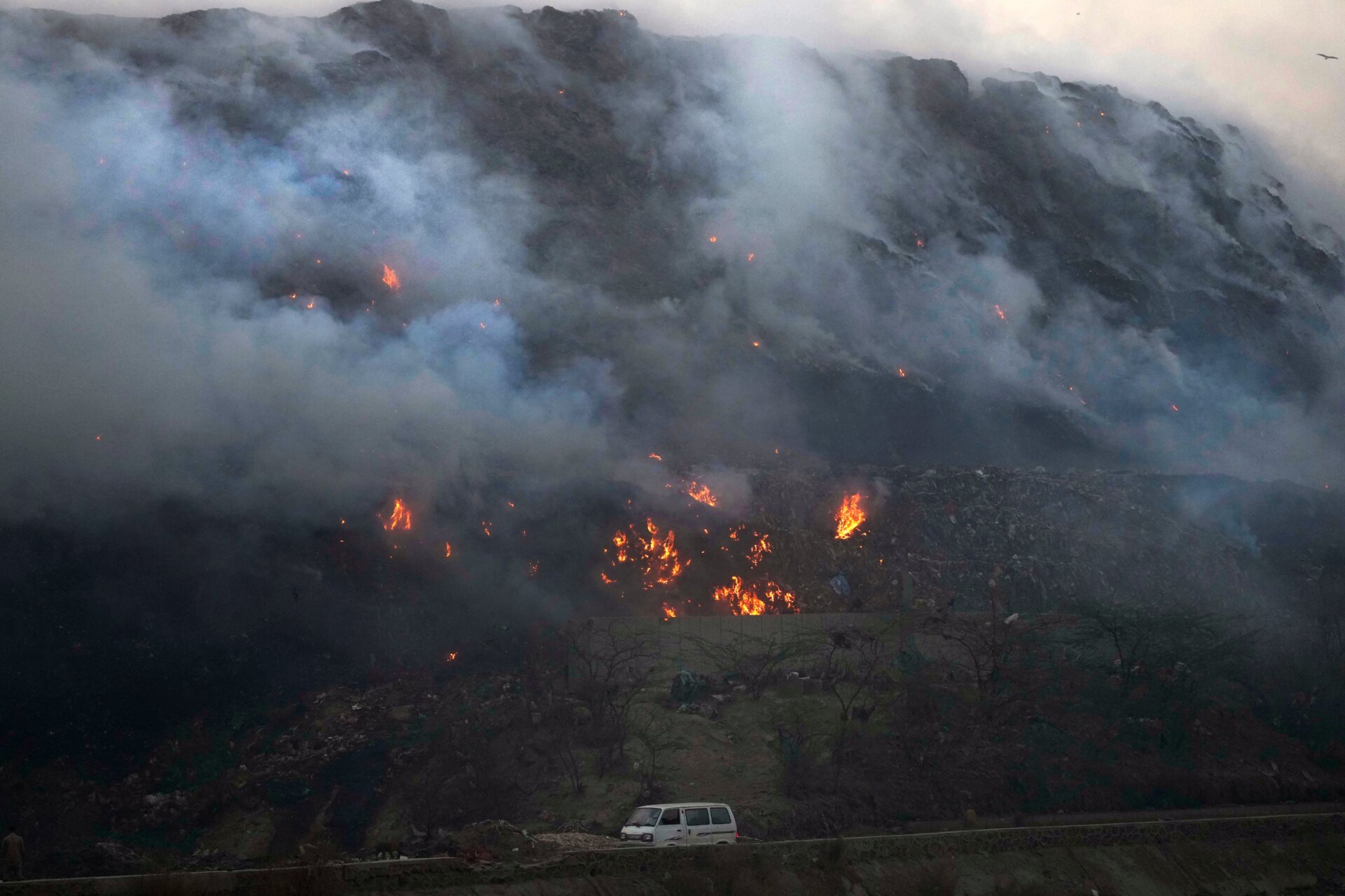 A van drives past the burning landfill.