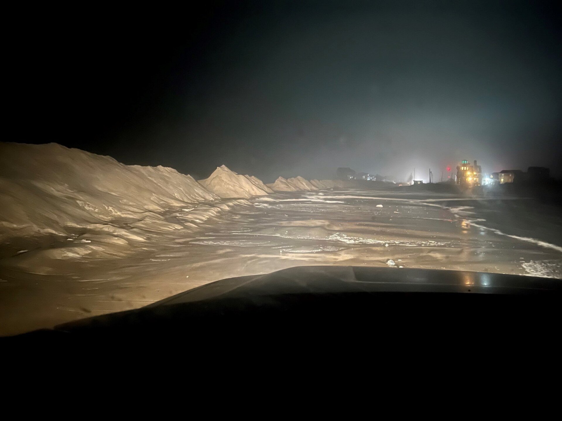 This nighttime photo shows high tides bringing water over sand dunes, causing road closures and threatening structures.