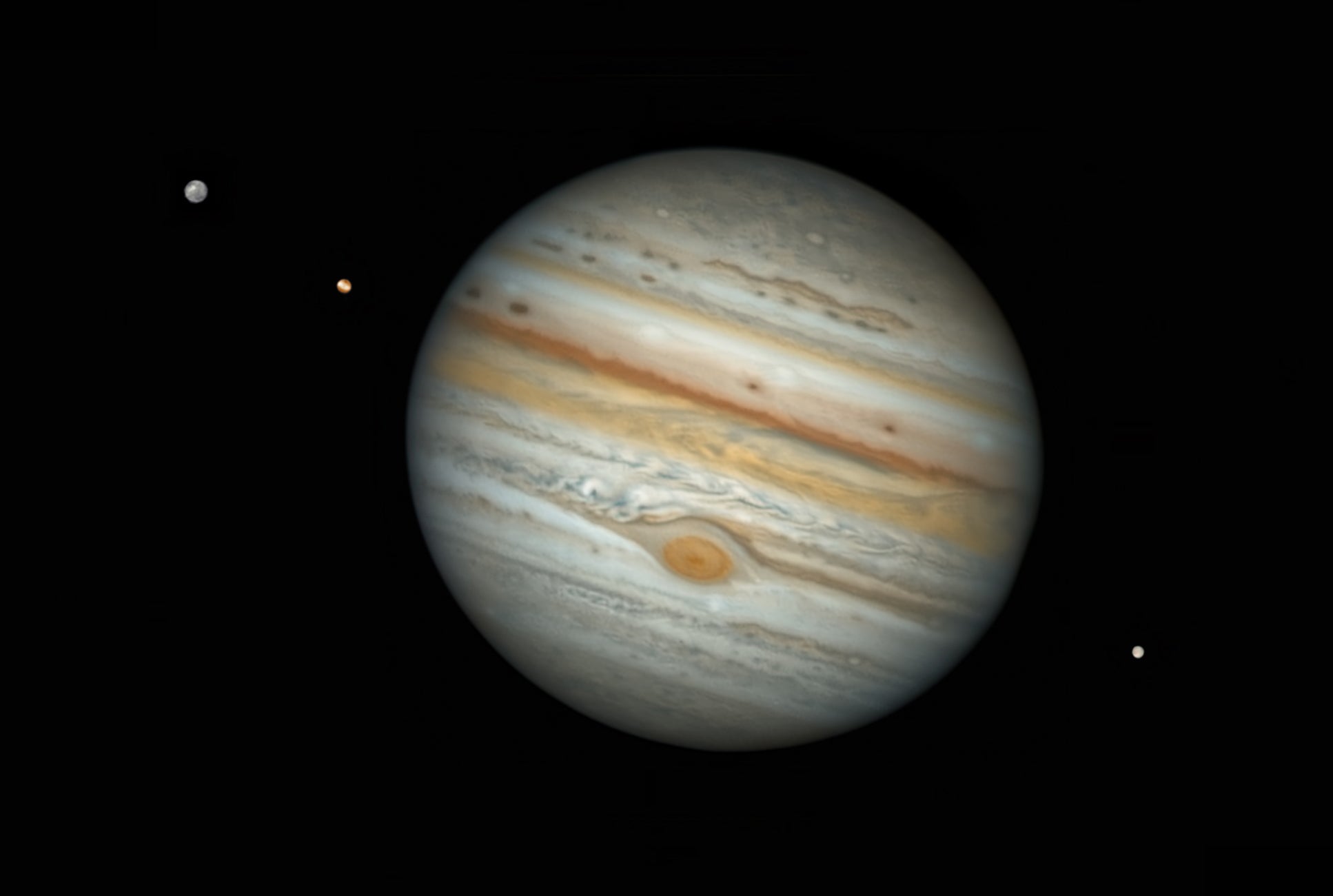 Jupiter (center) with two moons to its left and one to its right.