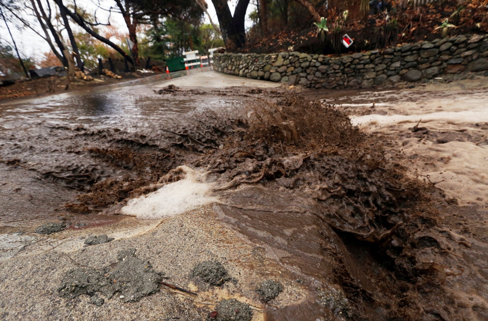 Wildfires are linked to lower water quality. Debris-filled water rushes across a street following the 2018 Woolsey Fire in Southern California.