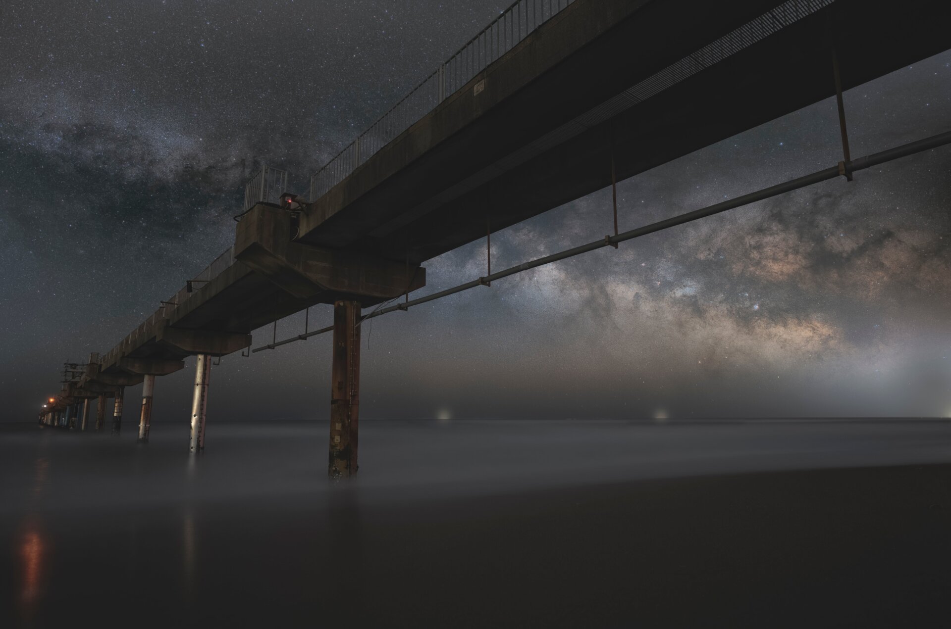 A pier in Japan in the foreground, the Milky Way behind it.