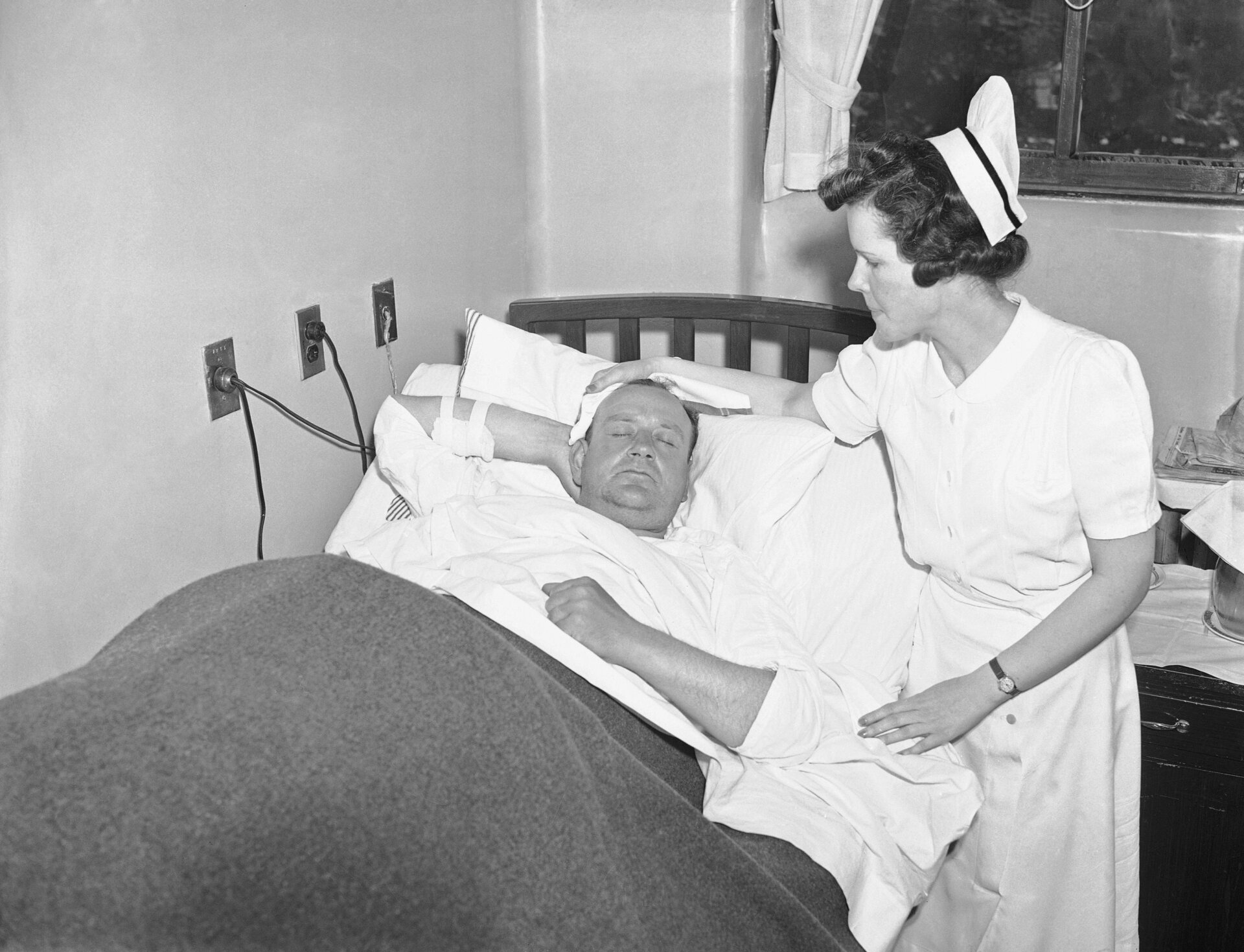 Nurse Alice Barrow watches detective Martin Schuchman of Queens, one of  three detectives injured on July 4, when a bomb being carried away from  the British pavilion in the World’s Fair at New York exploded killing  two policemen.