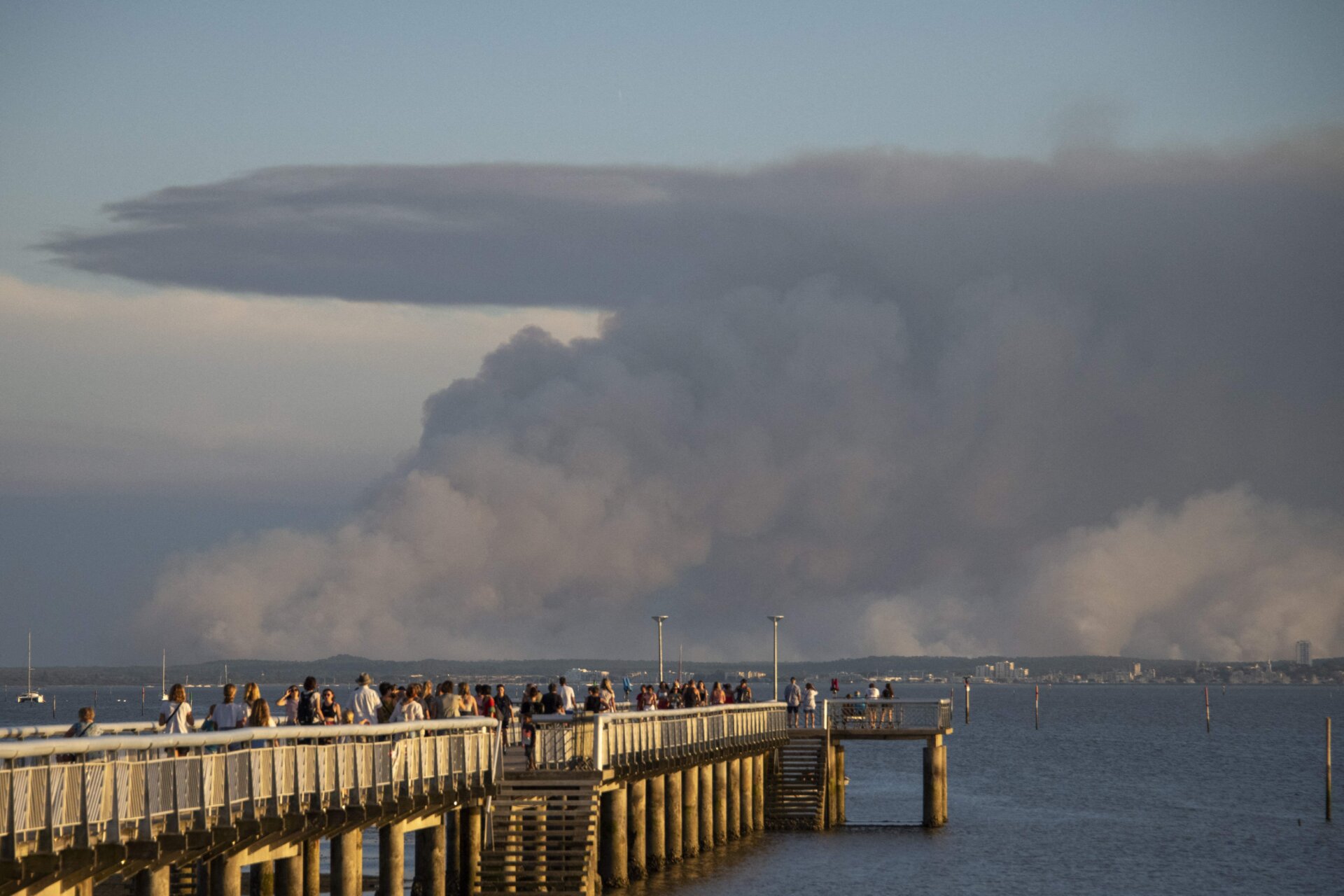 Tourists in Andernos-les-Bains look at wildfire smoke billowing from a fire in La Teste in southwestern France, on July 14, 2022. 