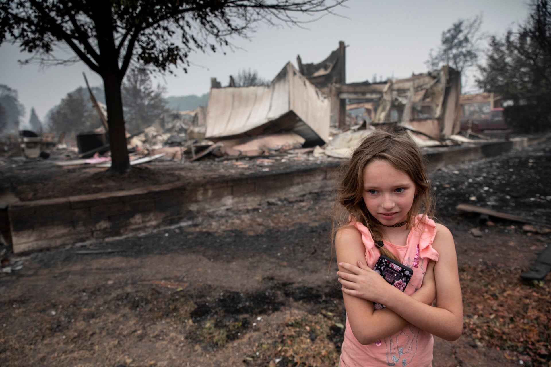 Ellie Owens, 8, stands in front of wildfire damage in Talen, Oregon. 