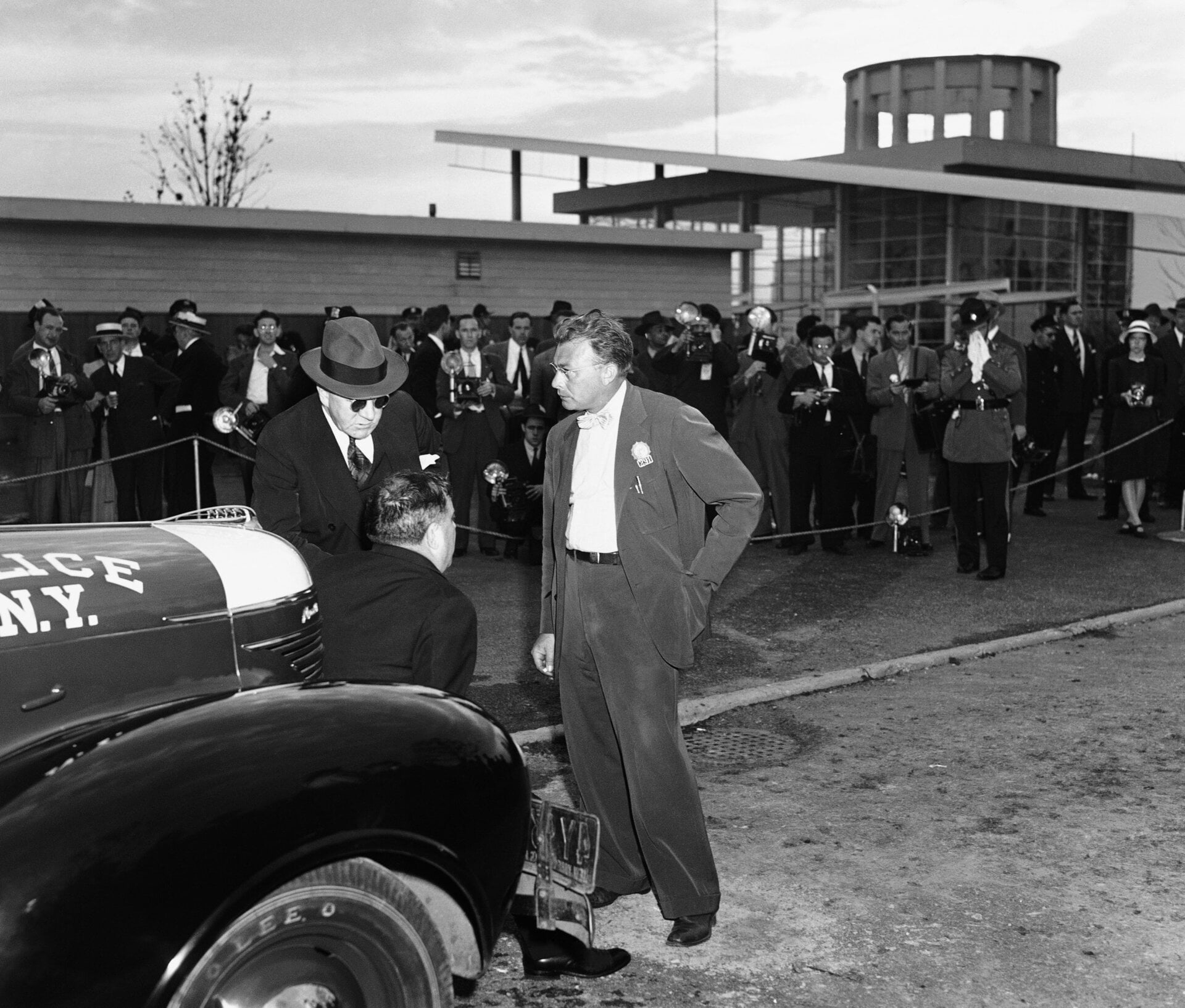 Detective Fred Morelock, right, explains to Mayor F. H. LaGuardia,  seated on auto bumper, and police commissioner Lewis J. Valentine, left,  how he removed a time bomb from the British pavilion at the New York  world’s fair on July 4, 1940 after it had been found by an attendant.