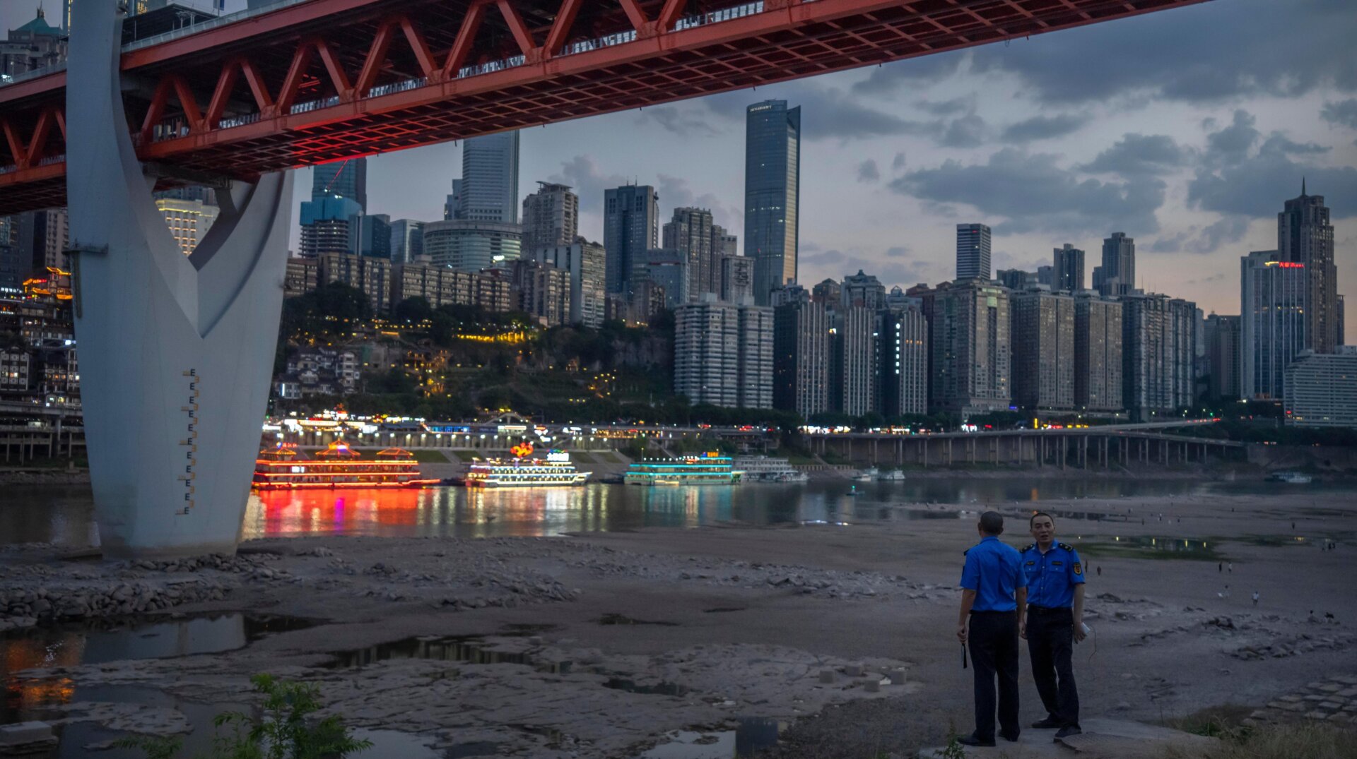 Security officers stand in the dried-out riverbed of the Jialing River in Chonqing on August 20.