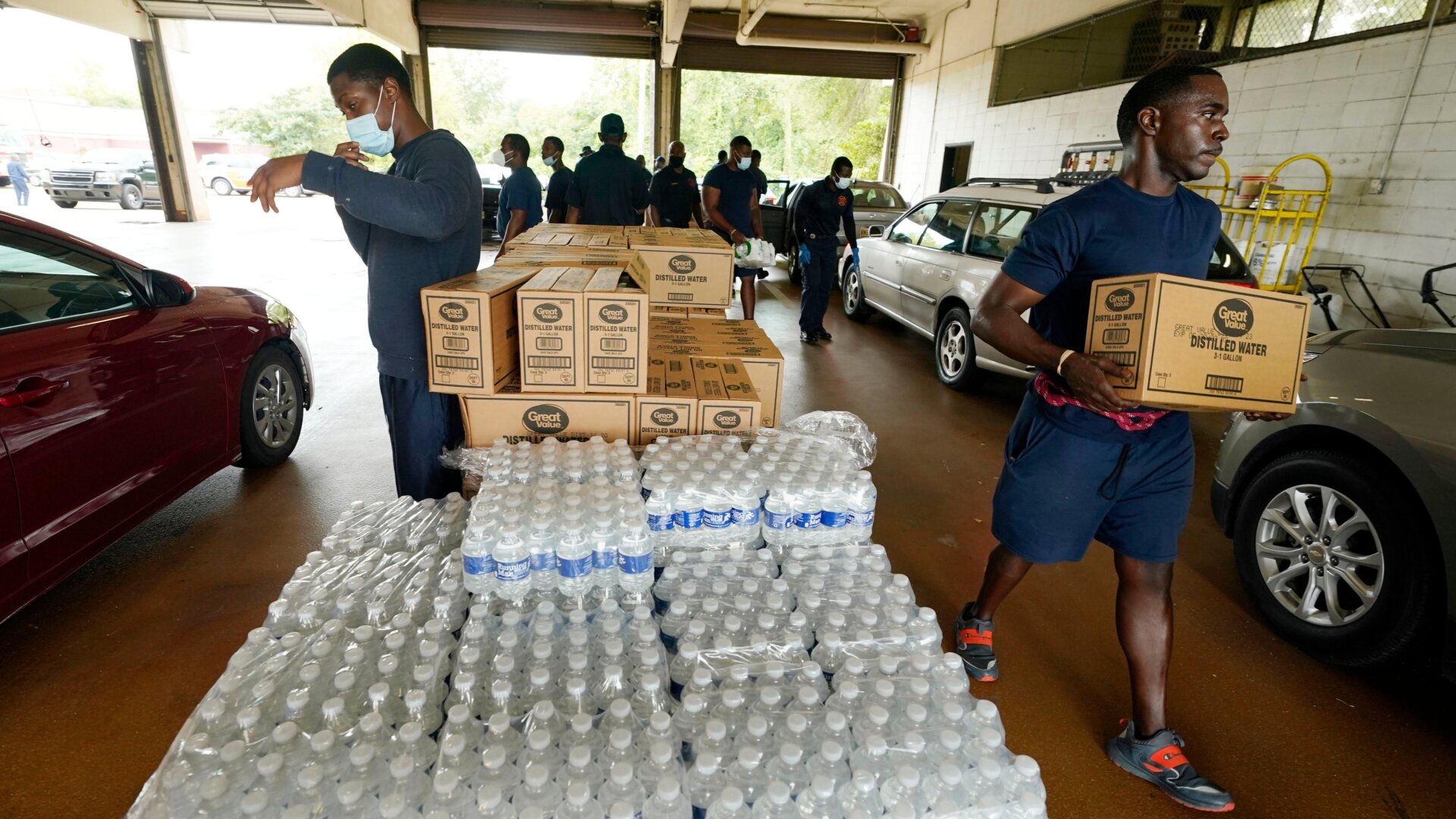 Firefighters and recruits for the Jackson, Miss., Fire Department carry cases of bottled water to residents vehicles, Aug. 18, 2022, as part of the city’s response to longstanding water system problems.