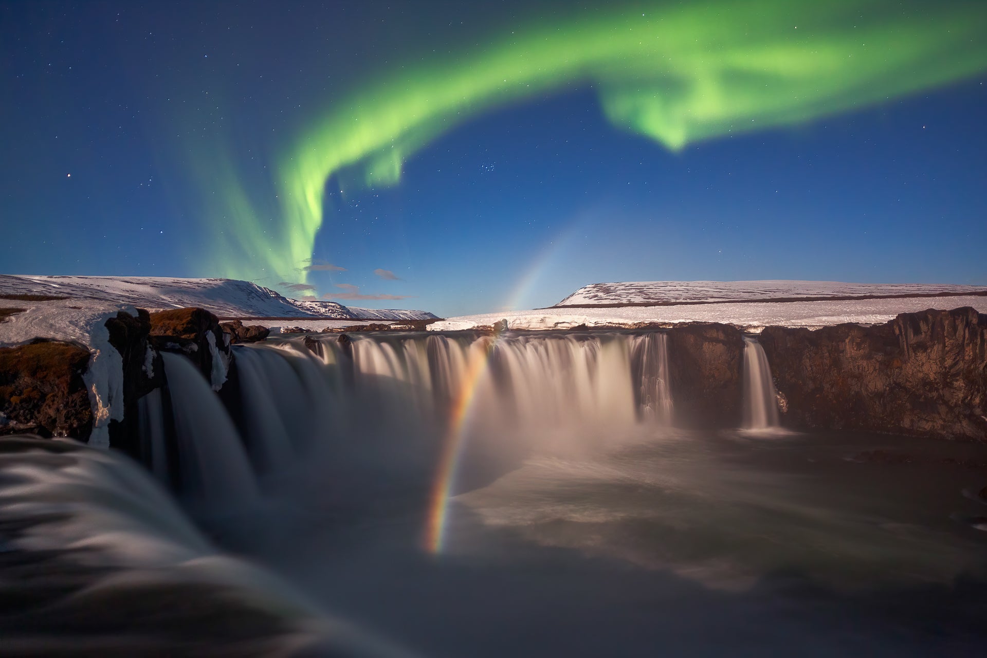 A dazzling shot of the aurora, a rainbow, and a waterfall.
