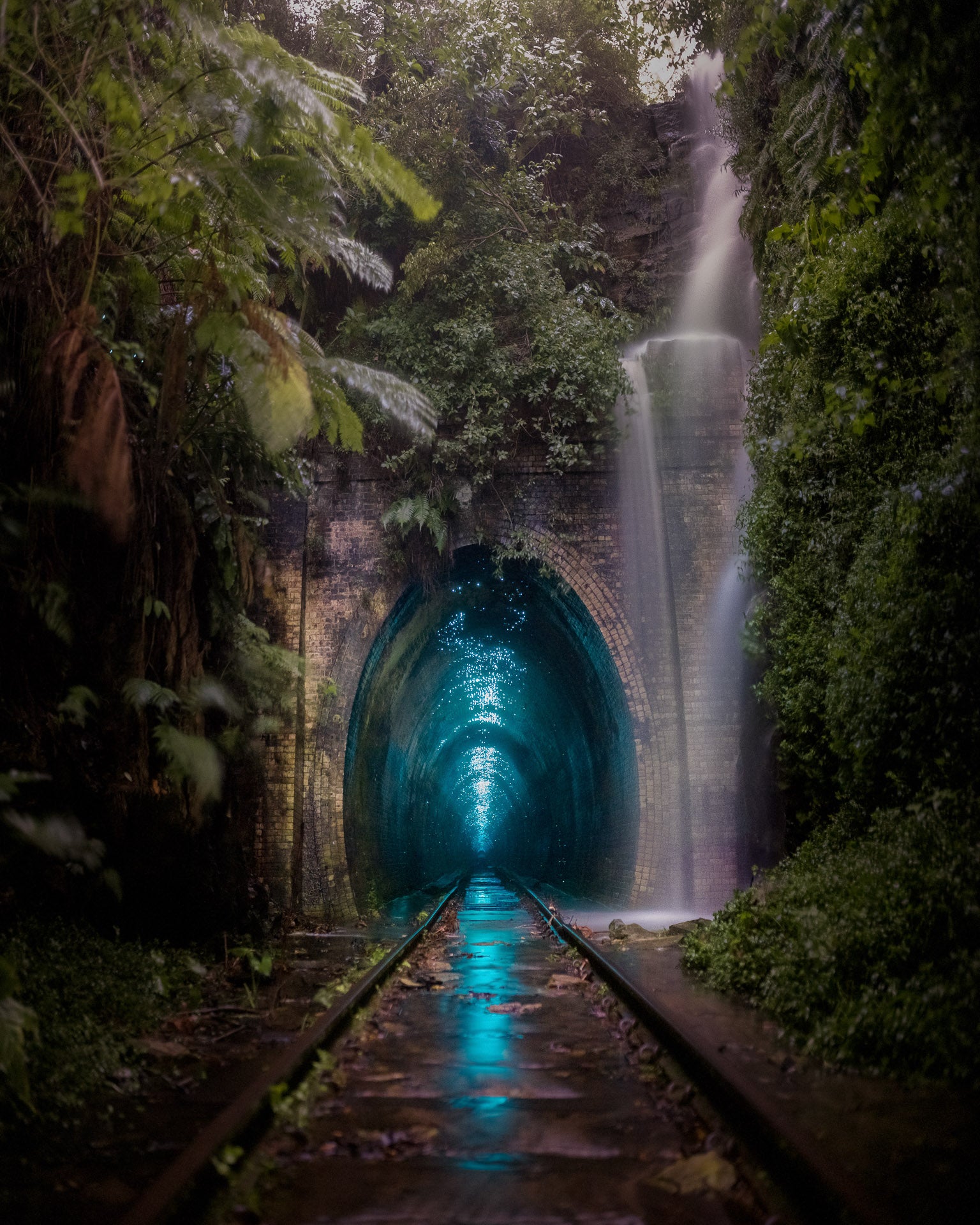 An abandoned rail tunnel glows in the rain.