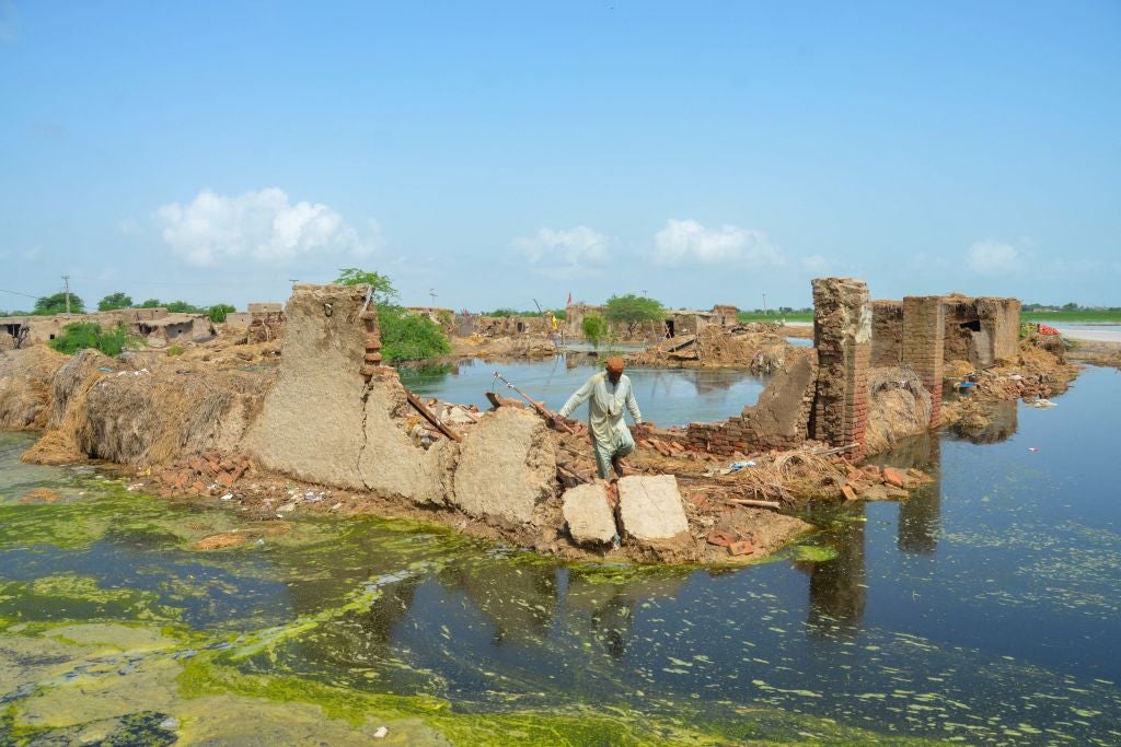 A  man walks over his collapsed mud house after heavy monsoon rains in Jaffarabad district, Balochistan province, on August 28, 2022. 
