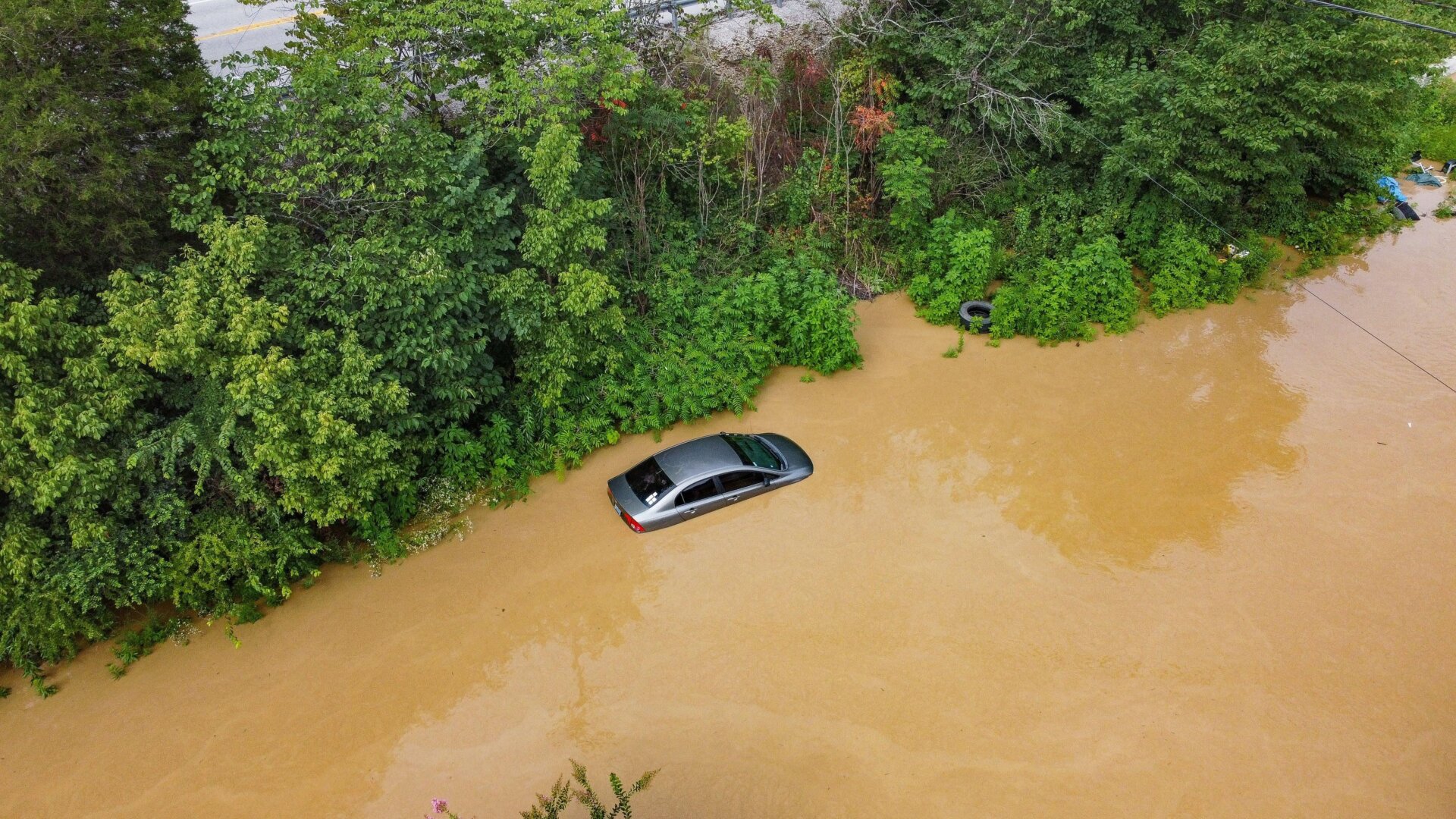 Aerial view of a car on a road submerged under flood waters from the North Fork of the Kentucky River in Jackson, Kentucky, on July 28, 2022.
