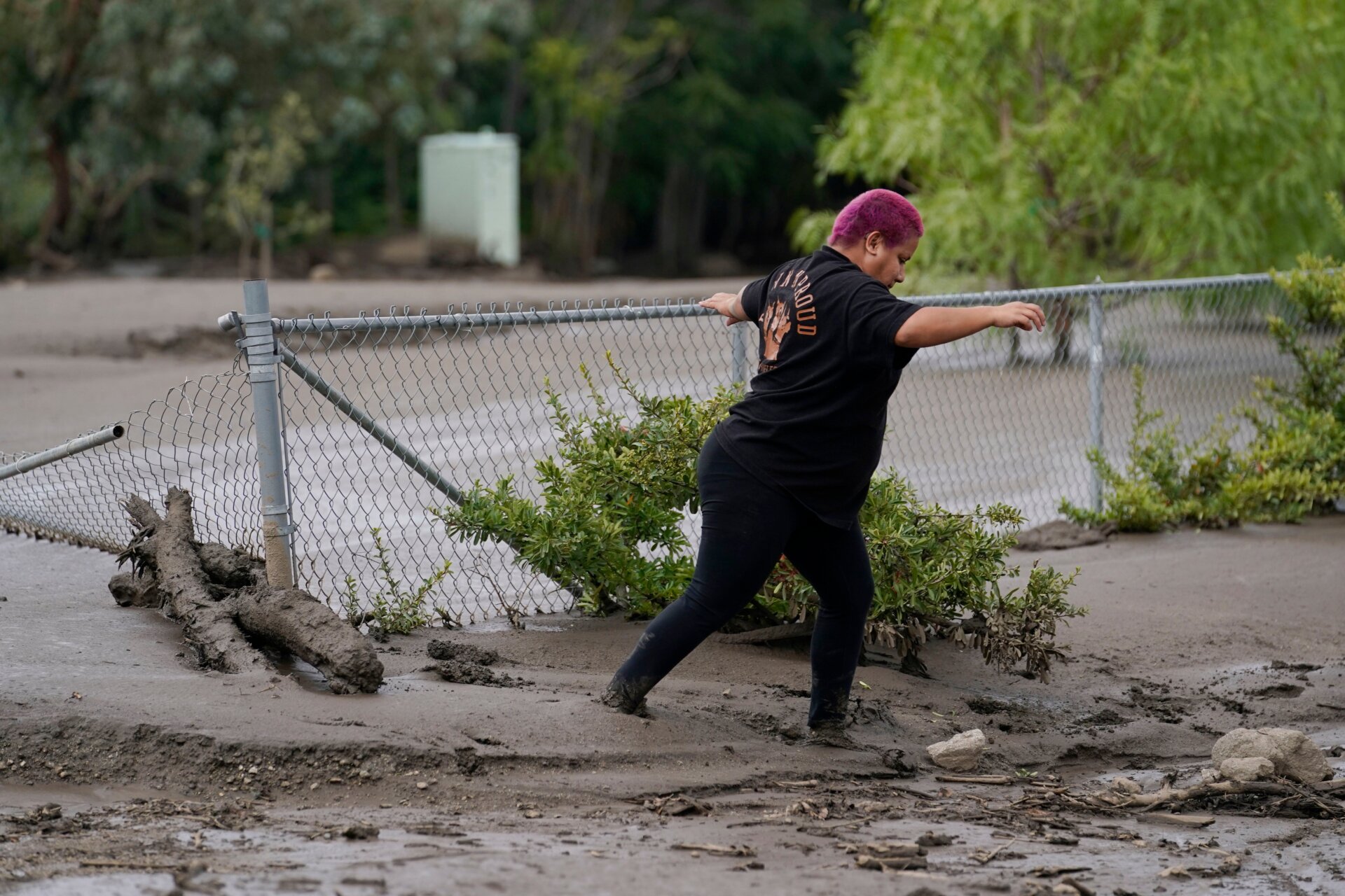 Local resident Perla Halbert walks through the mud along her driveway in the aftermath of a mudslide on Tuesday, Sept. 13, 2022, in Oak Glen, California. 