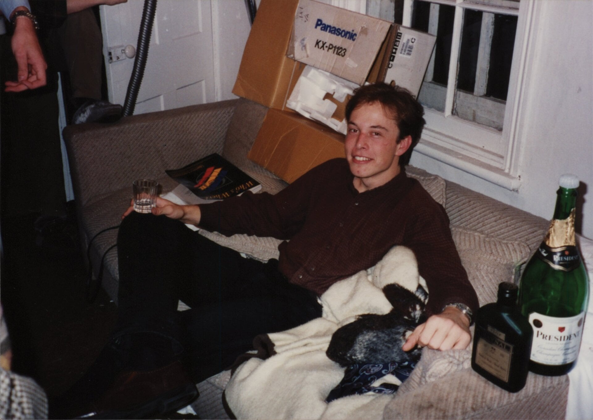 Musk having a drink while seated on the couch in his brother’s student apartment. 