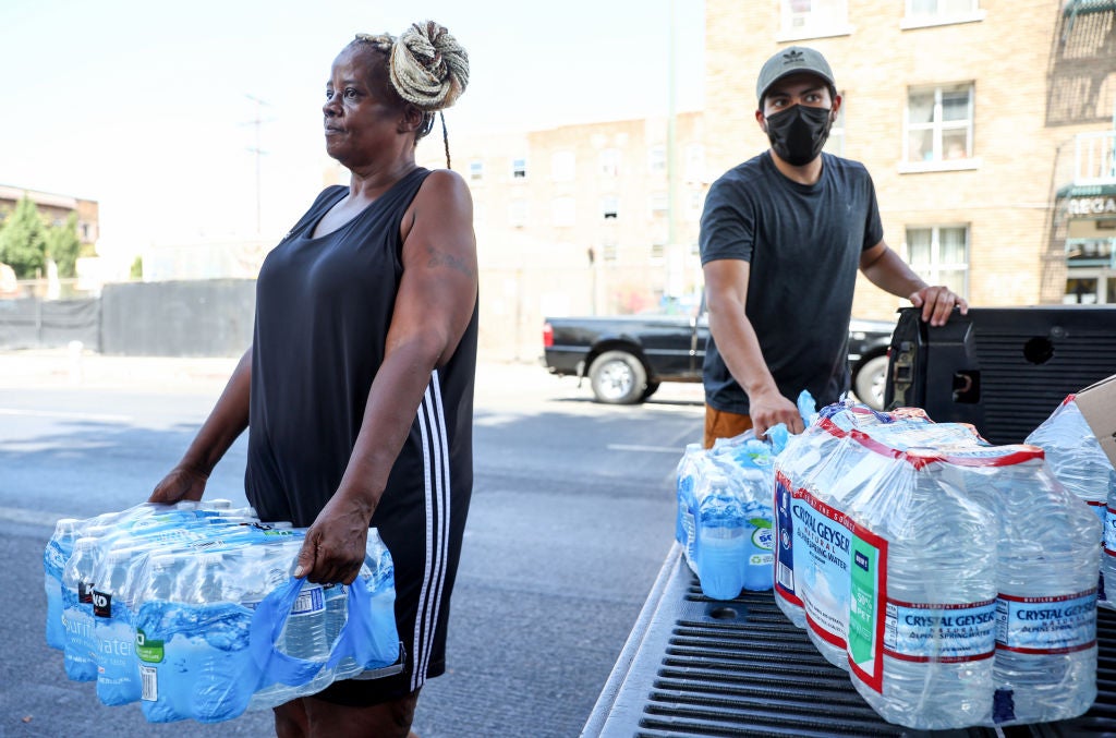 A member of the Skid Row community carries away water distributed by volunteers with Water Drop LA on September 4, 2022 as temperatures hovered around 100 degrees in Los Angeles, California. 
