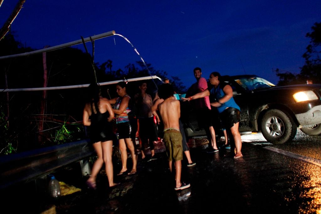 People affected by Hurricane Maria collect water while others bathe using an improvised water system for water pipes from a mountain creek in Utuado, Puerto Rico on October 17, 2017.
